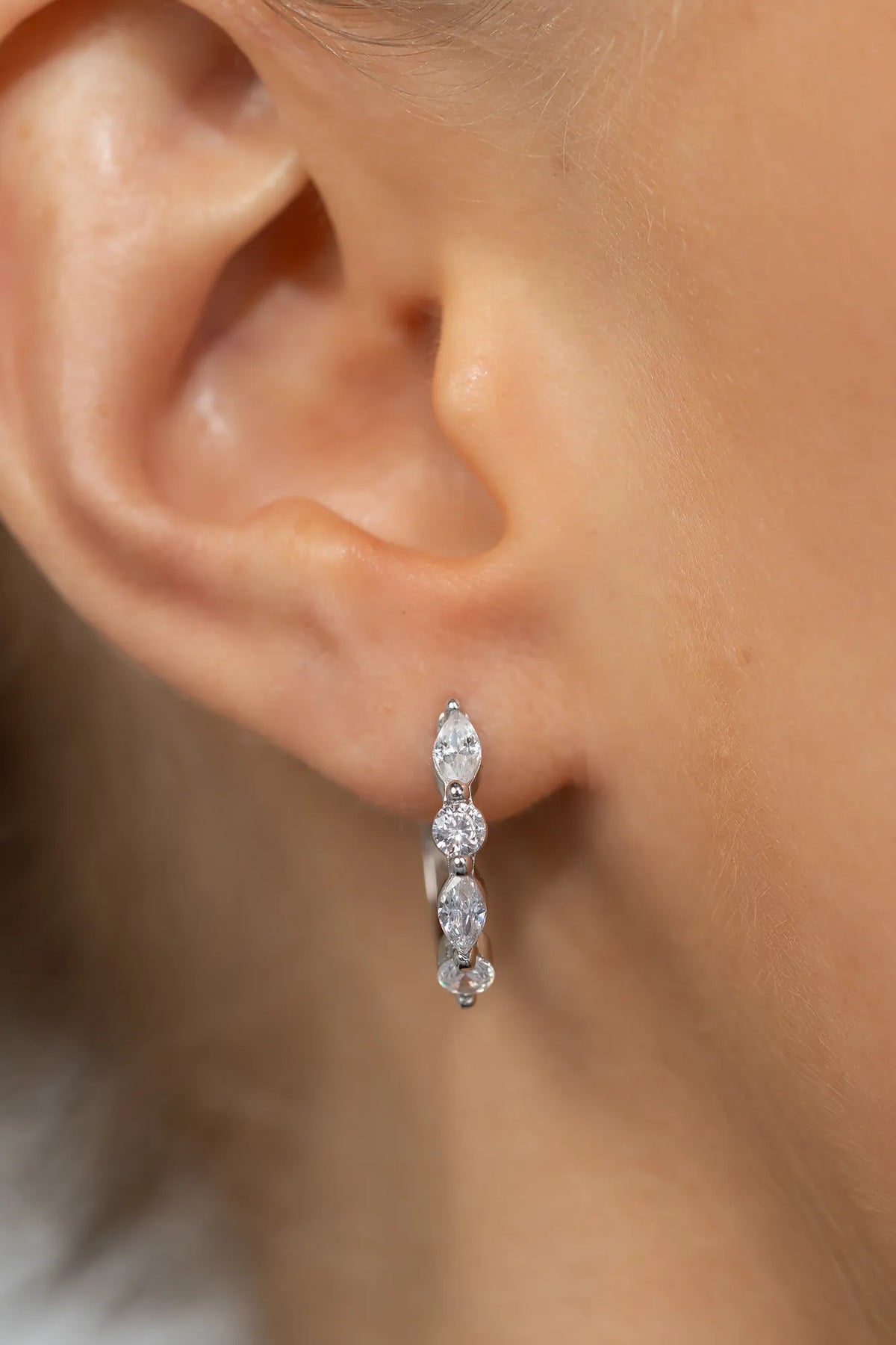 Silver hoop earrings adorned with clear crystal stones in mixed round and marquise shapes.