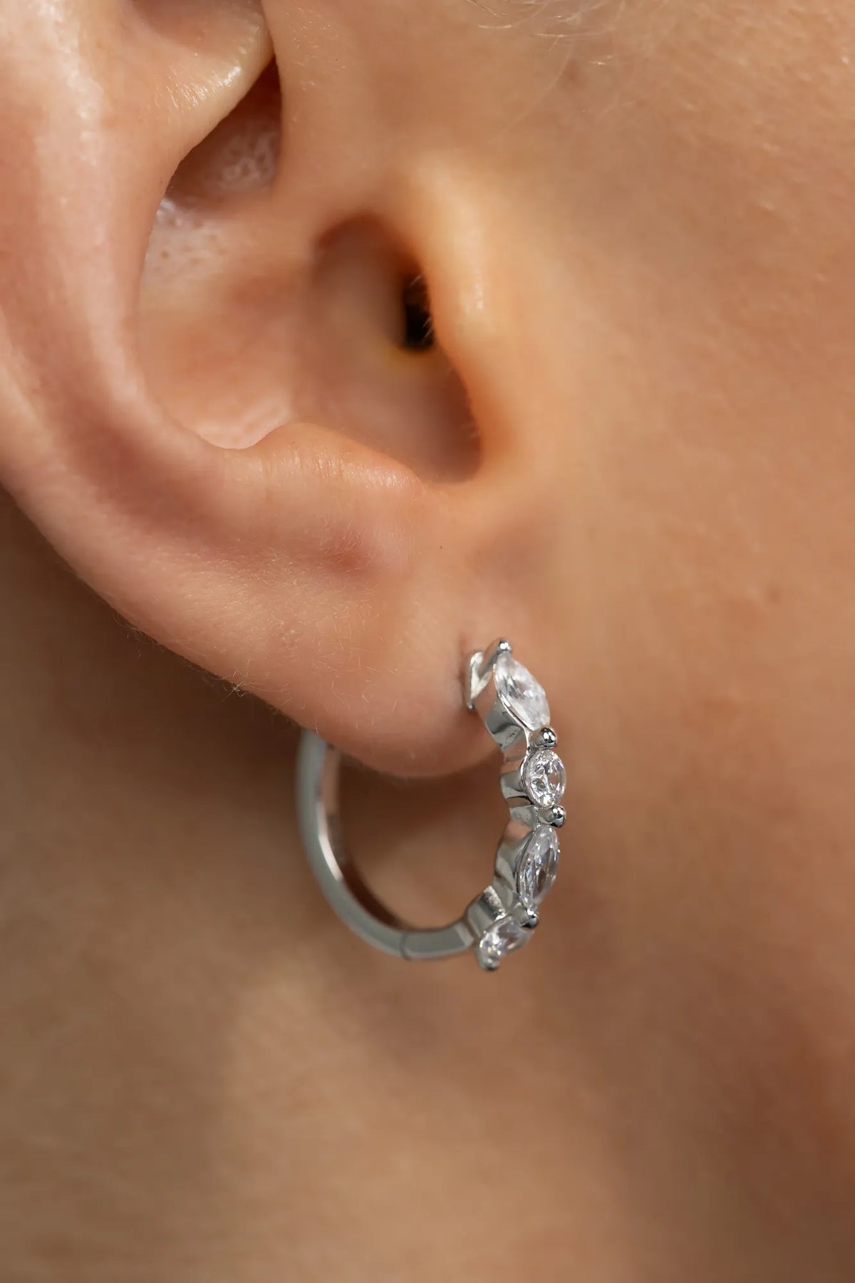 Silver hoop earrings adorned with clear crystal stones in mixed round and marquise shapes.
