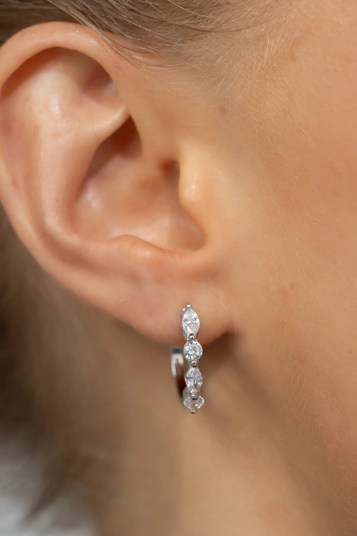 Silver hoop earrings adorned with clear crystal stones in mixed round and marquise shapes.