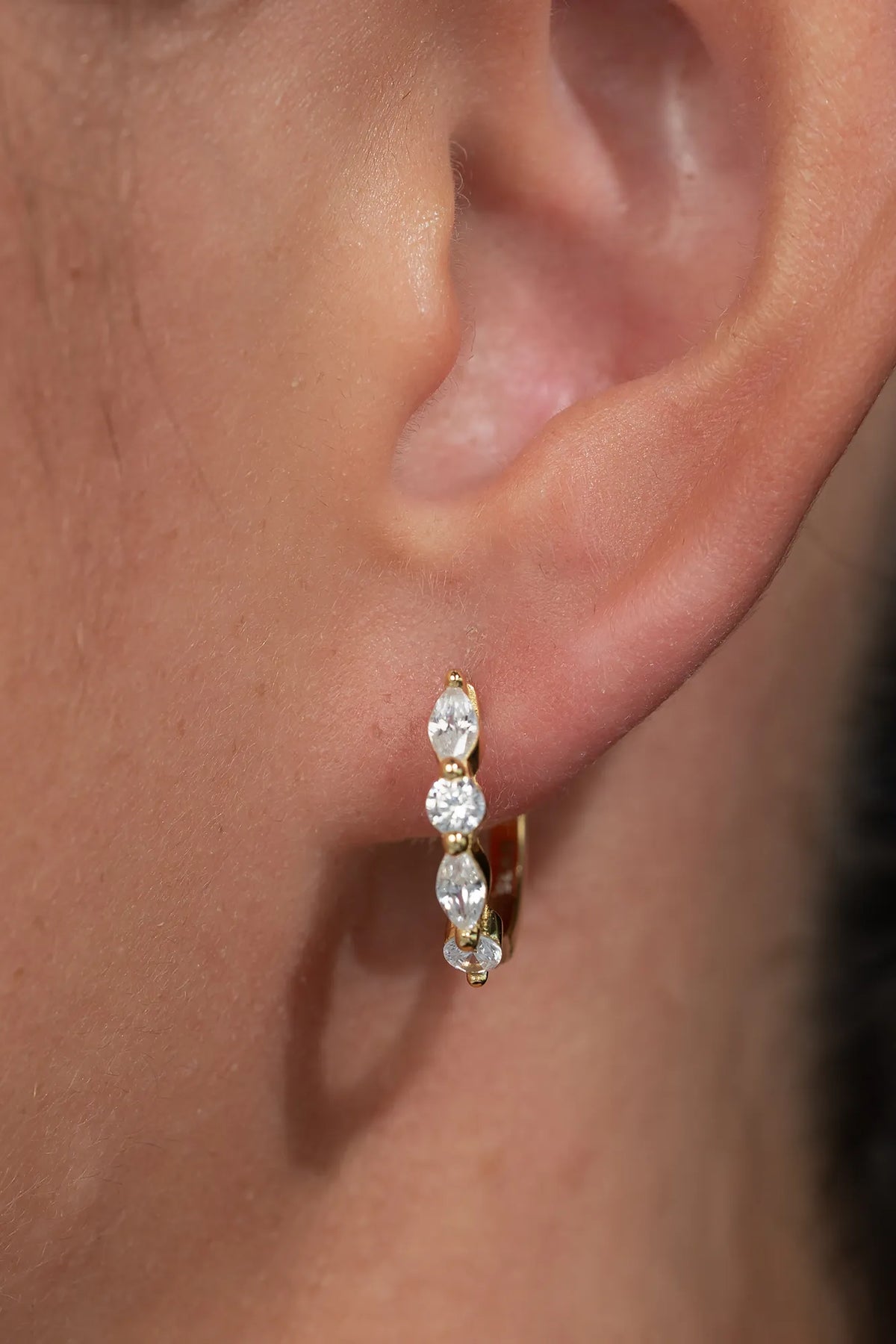 Gold hoop earrings adorned with clear crystal stones in mixed round and marquise shapes.