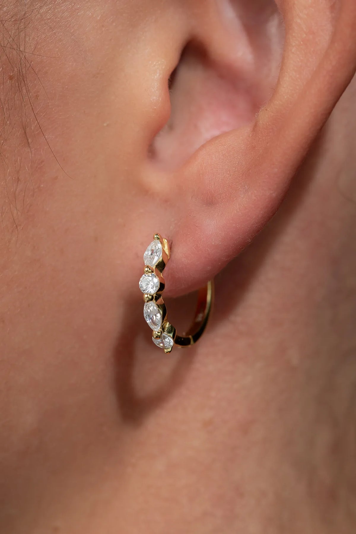 Gold hoop earrings adorned with clear crystal stones in mixed round and marquise shapes.