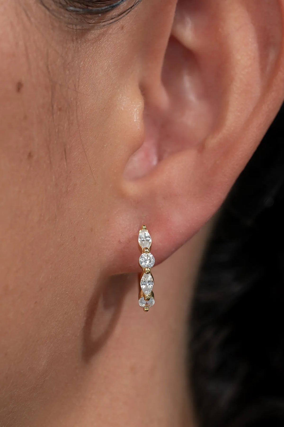 Gold hoop earrings adorned with clear crystal stones in mixed round and marquise shapes.