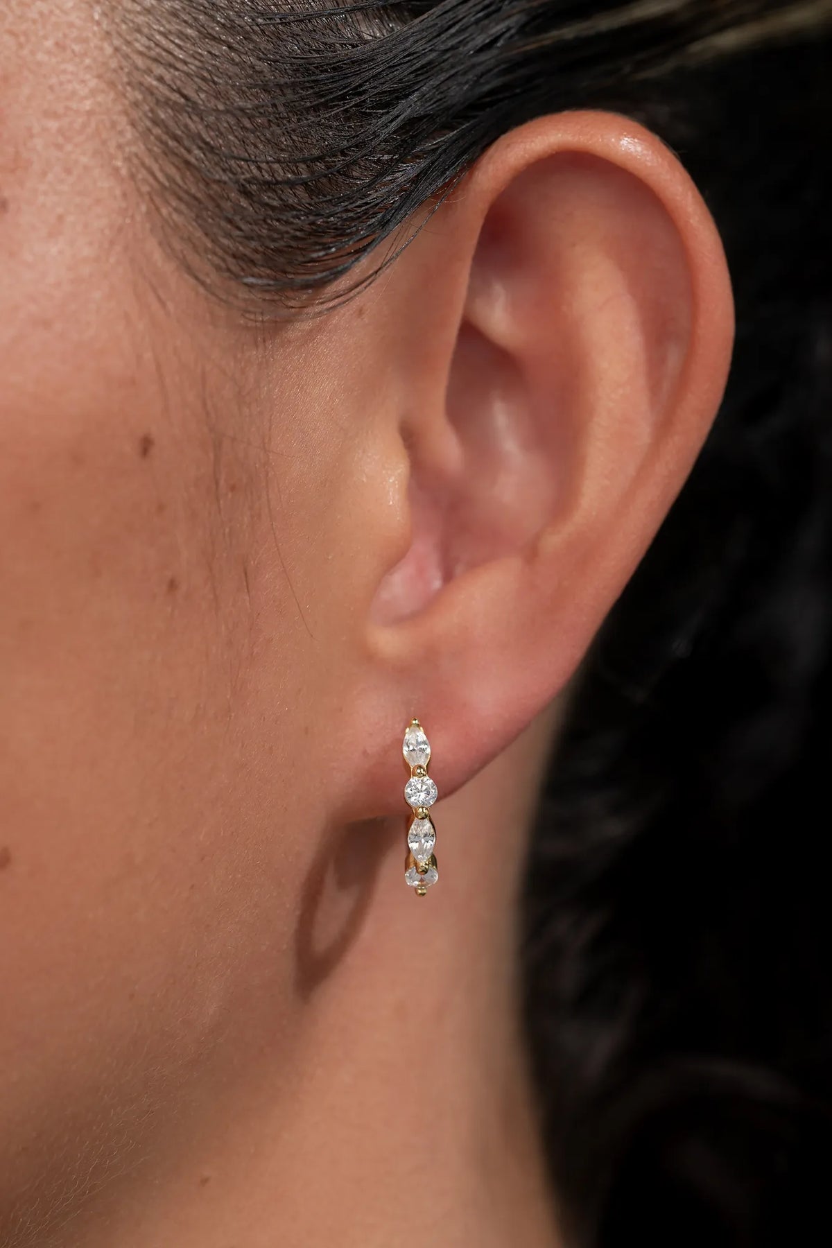 Gold hoop earrings adorned with clear crystal stones in mixed round and marquise shapes.
