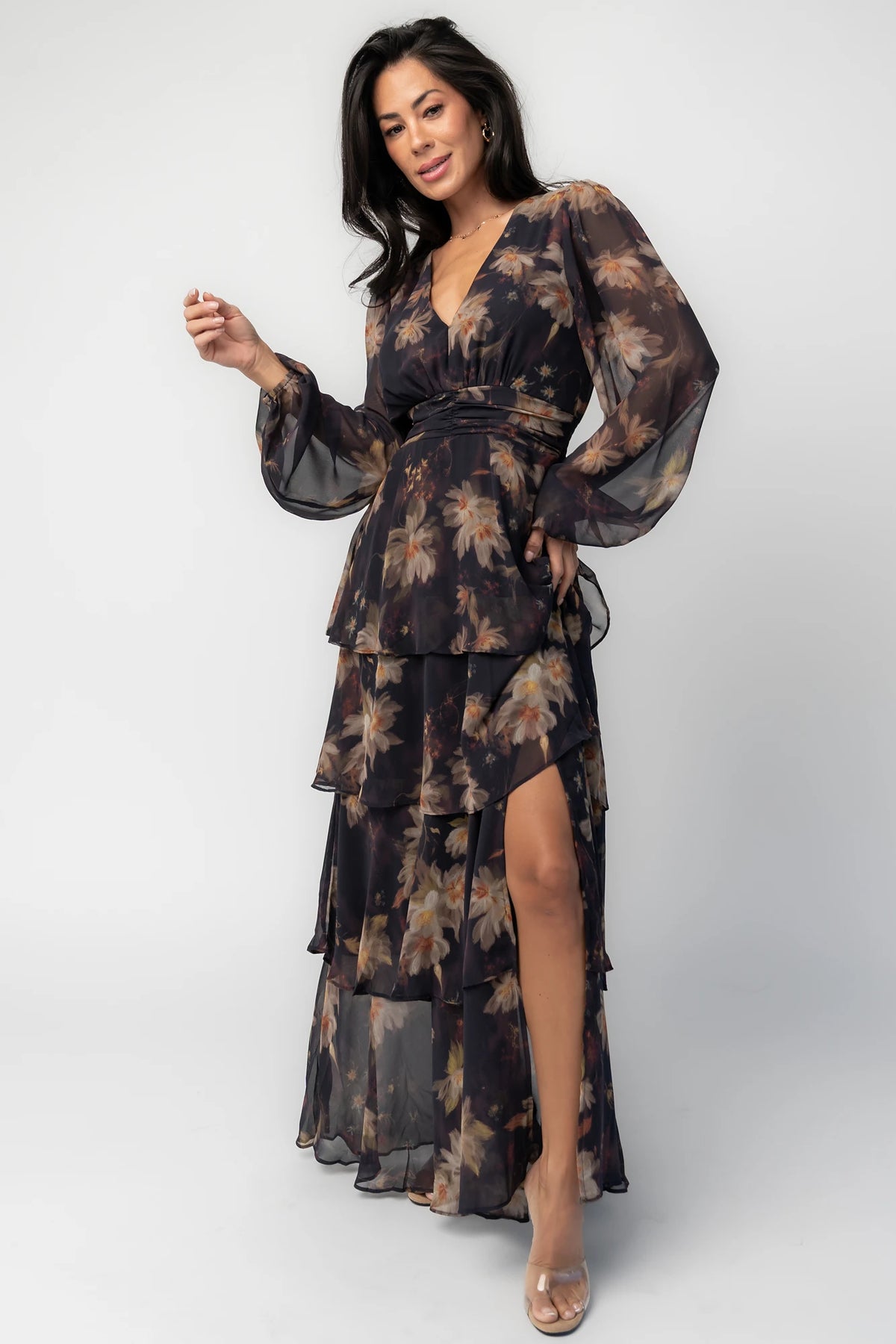 Model wearing the Mariella Tiered Maxi Dress featuring a V-neckline, long sheer puff sleeves, a smocked back waist, and a flowing tiered chiffon maxi skirt with a romantic floral print.