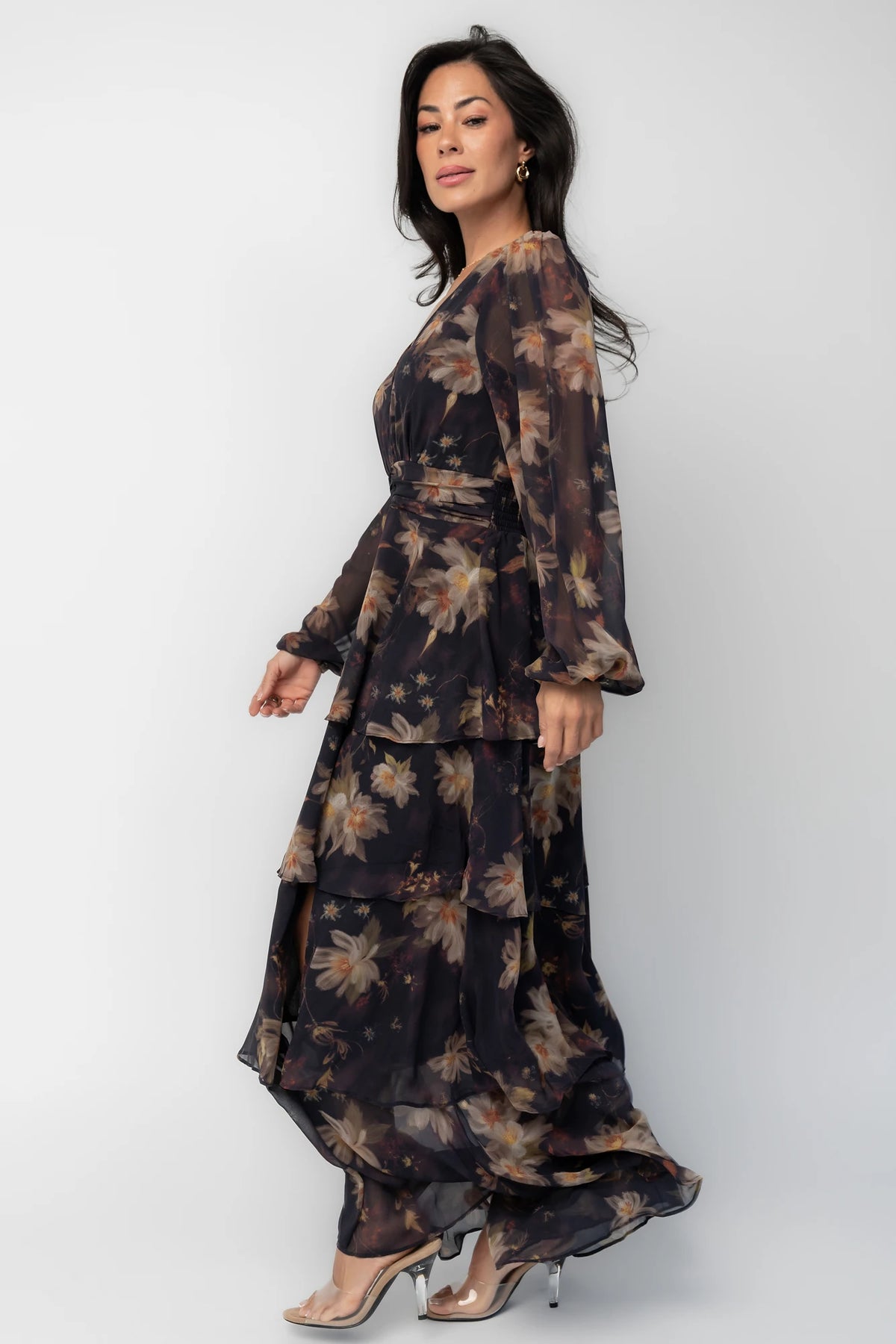 Model wearing the Mariella Tiered Maxi Dress featuring a V-neckline, long sheer puff sleeves, a smocked back waist, and a flowing tiered chiffon maxi skirt with a romantic floral print.