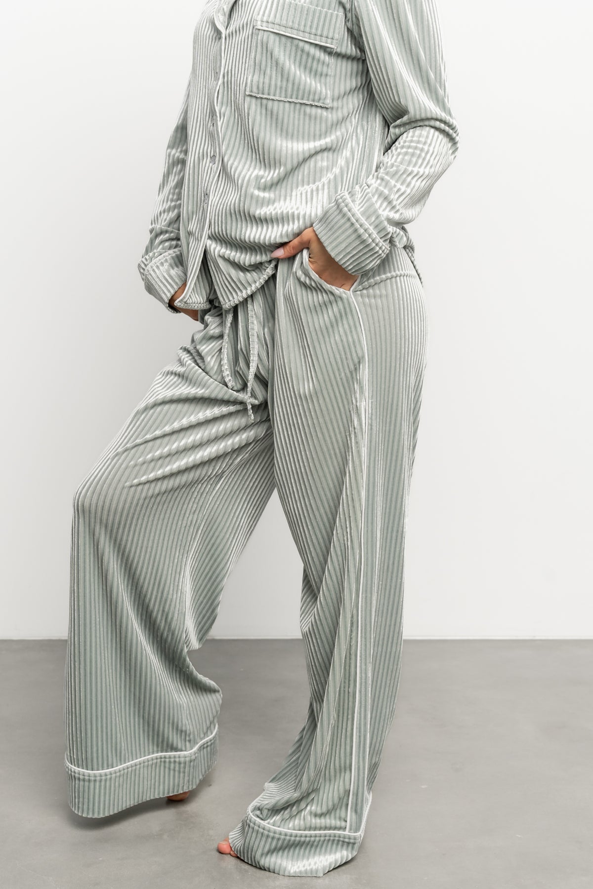 Close-up of ribbed velvet fabric texture in light sage, highlighting soft stretch and subtle vertical rib pattern.
