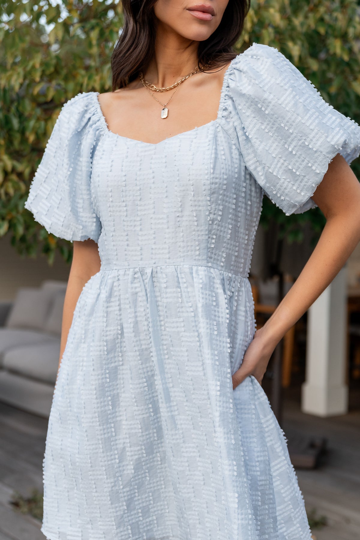 Lifestyle side view of Sommer Short Dress in light blue showing convenient side pocket, short length and flowing babydoll shape.