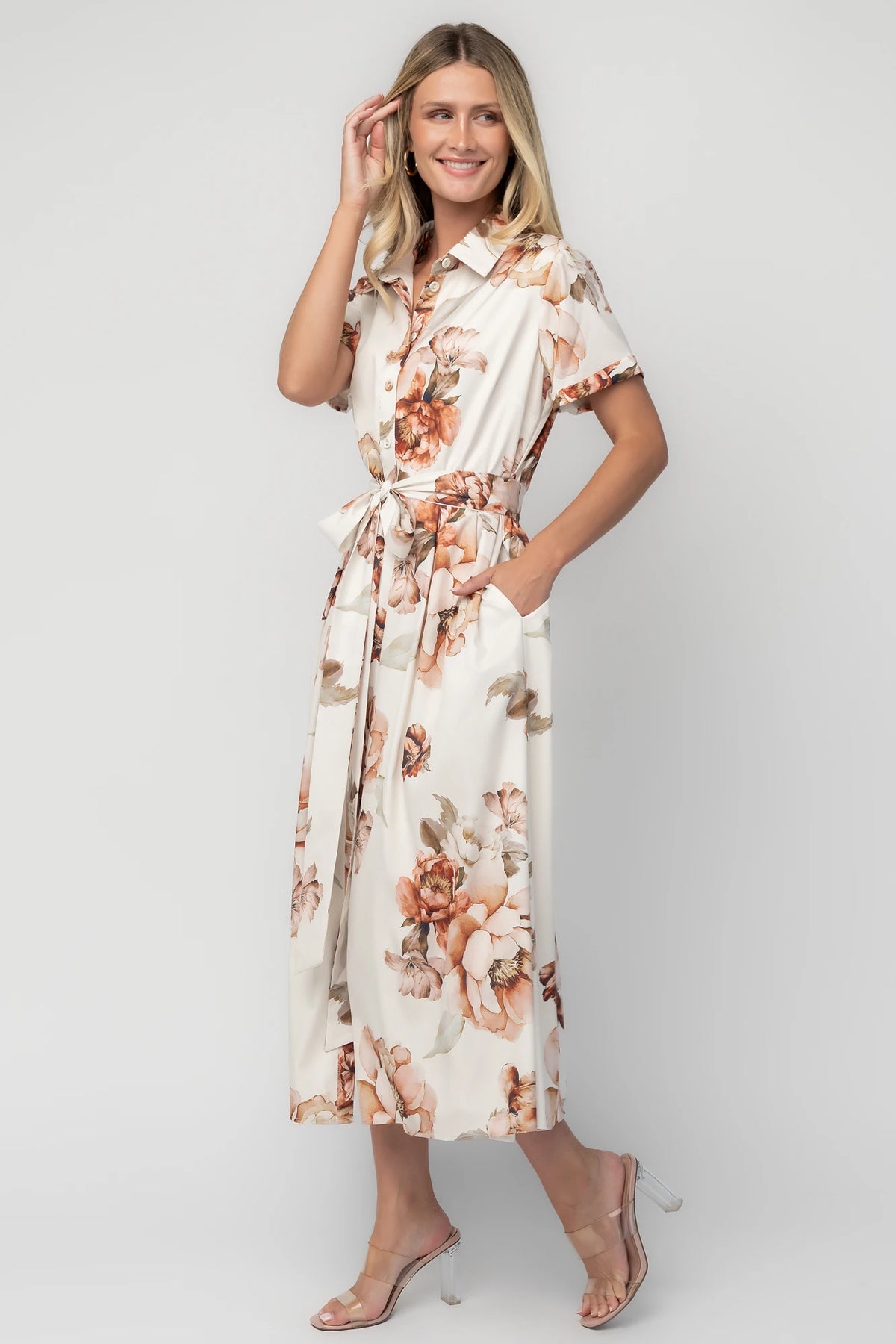 Model wearing the Blythe Midi Dress in Ivory Floral featuring a collared neckline, functional button-front bodice, short rolled sleeves, and a removable waist tie.