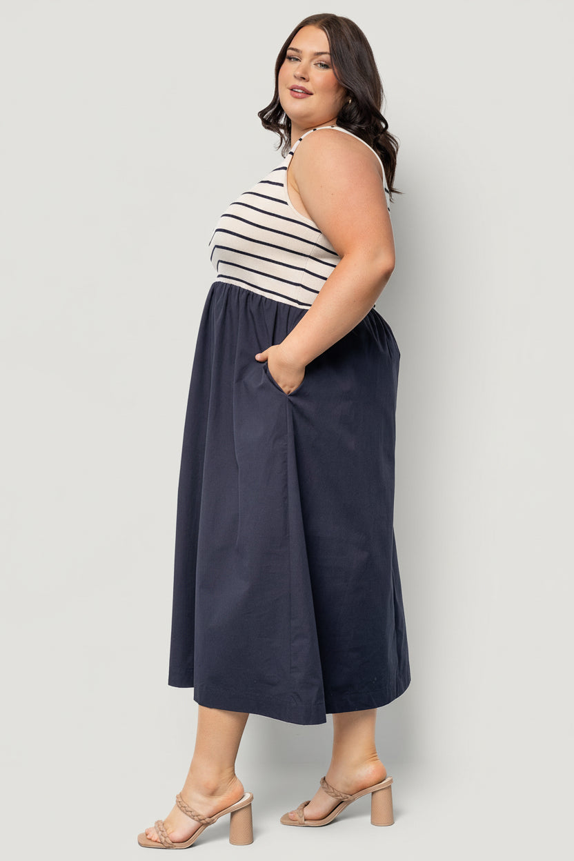 Side view of the navy stripe dress on model, showing natural elastic waist, discreet side pocket opening, and midi skirt drape.