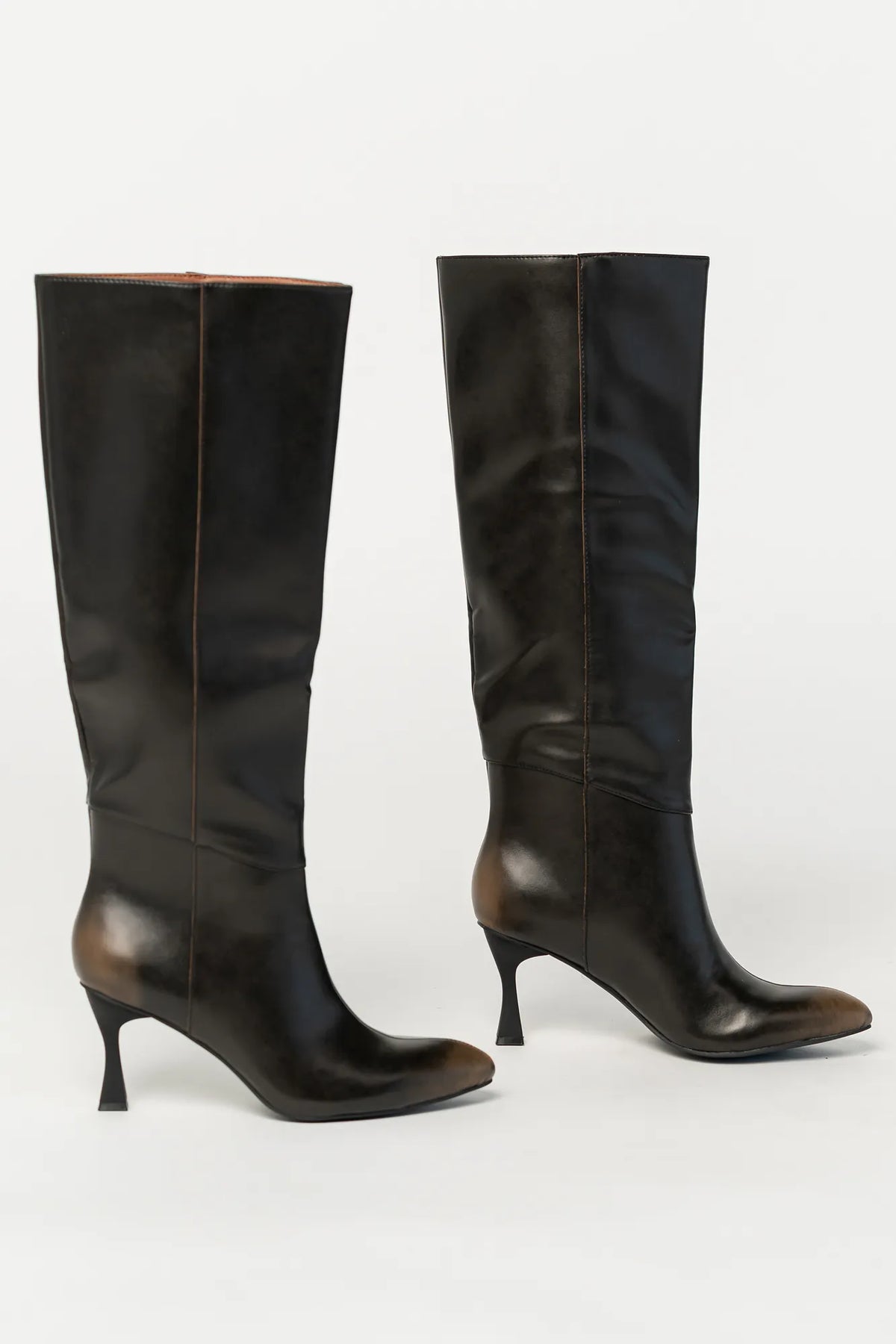 Pair of black knee-high boots featuring a pointed toe, sleek fitted shaft, and sculpted kitten heel. The streamlined silhouette and smooth finish create an elegant, versatile look that pairs effortlessly with dresses, skirts, and tailored outfits.