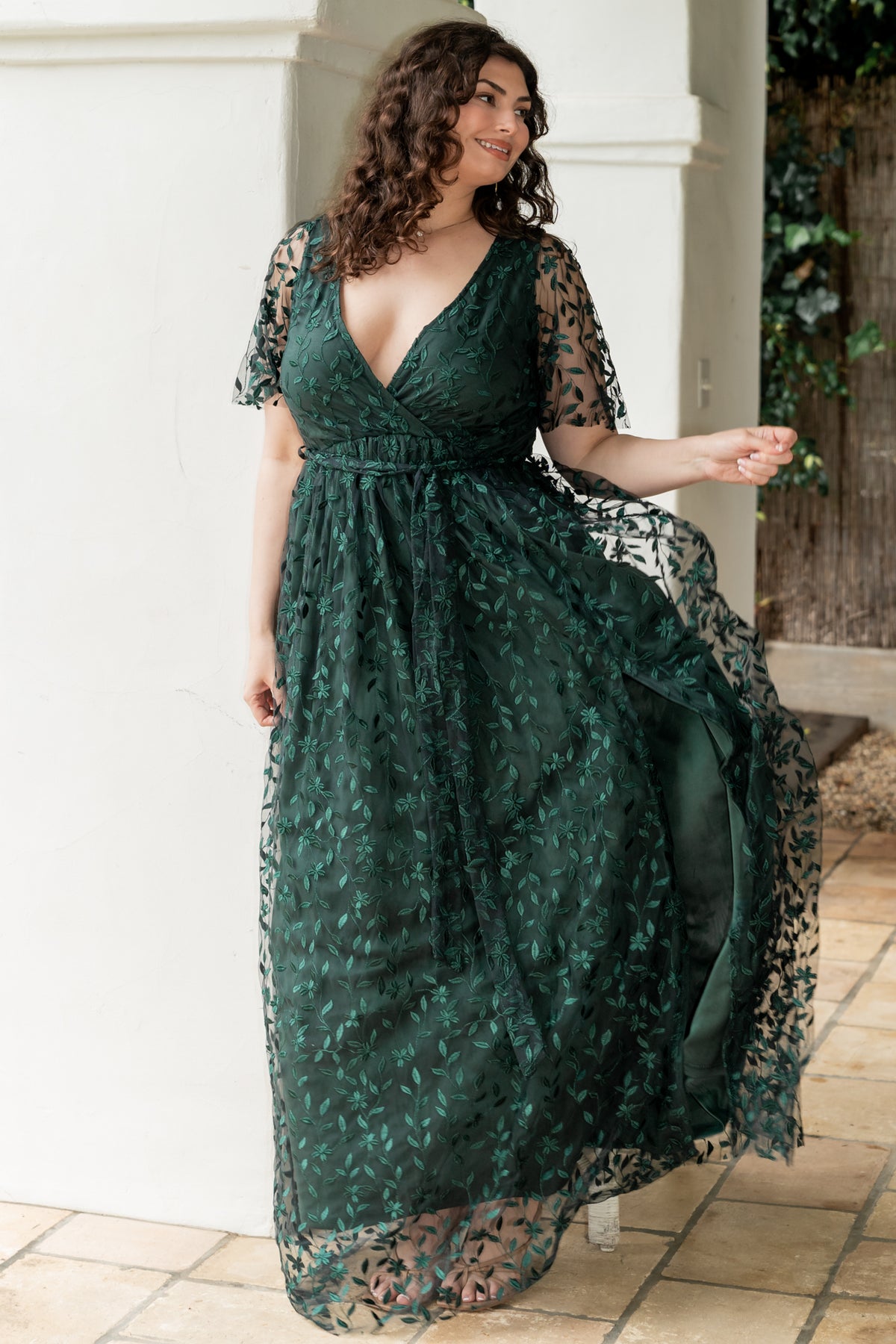 Side view of dark green maxi highlighting the left-leg slit, raw-cut hem, and the flow of the fully lined skirt as the model moves.