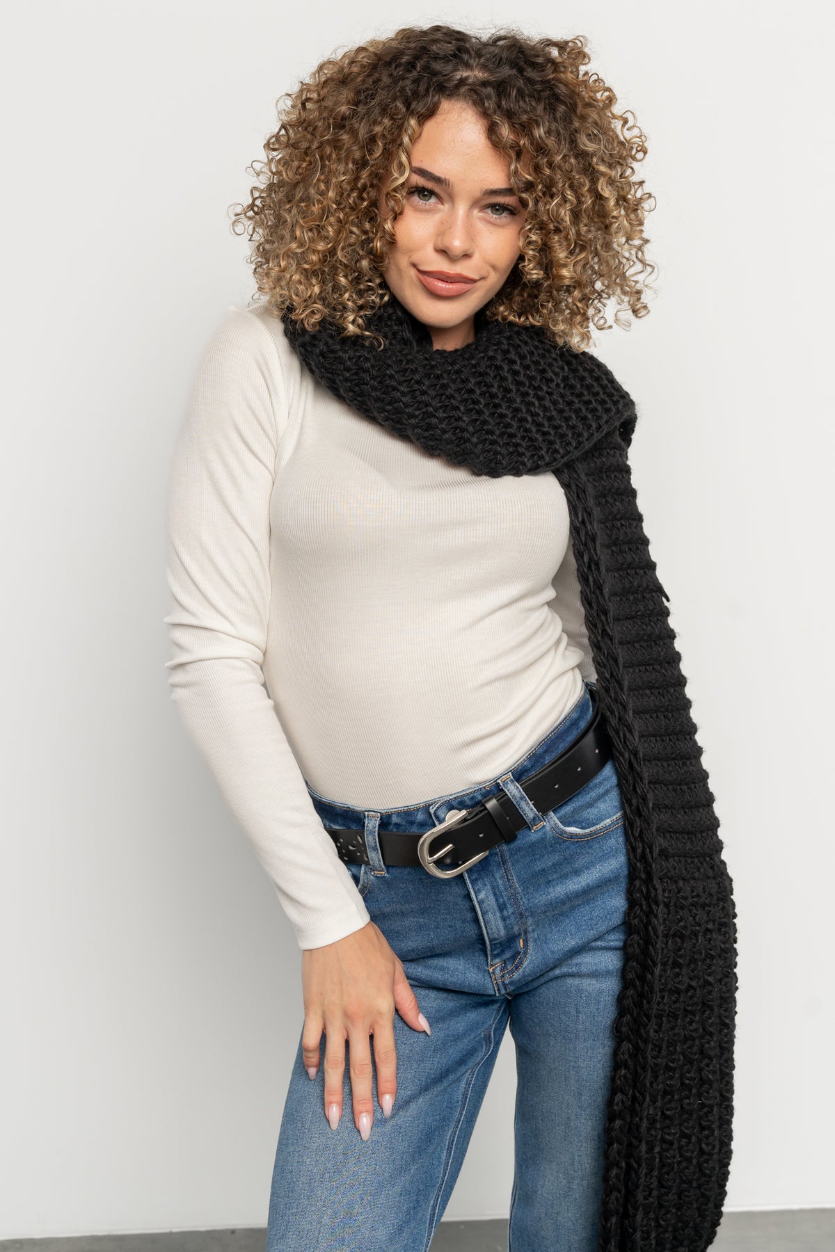 Styled look showing the black floral cutout belt paired with jeans and layered knitwear to illustrate versatile wear.