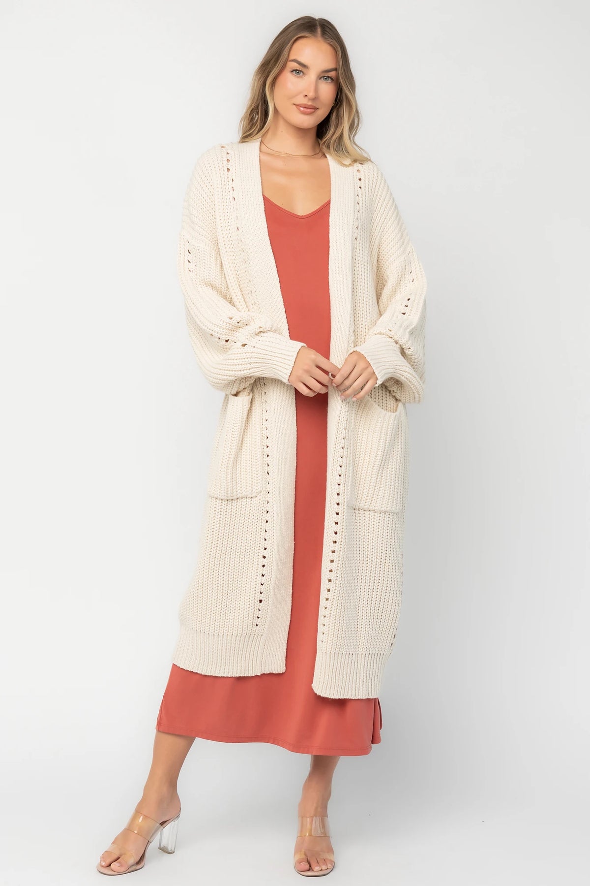 Natural chunky knit longline cardigan with an open front, pointelle detailing, balloon sleeves, ribbed trim, front patch pockets, and an oversized relaxed fit.