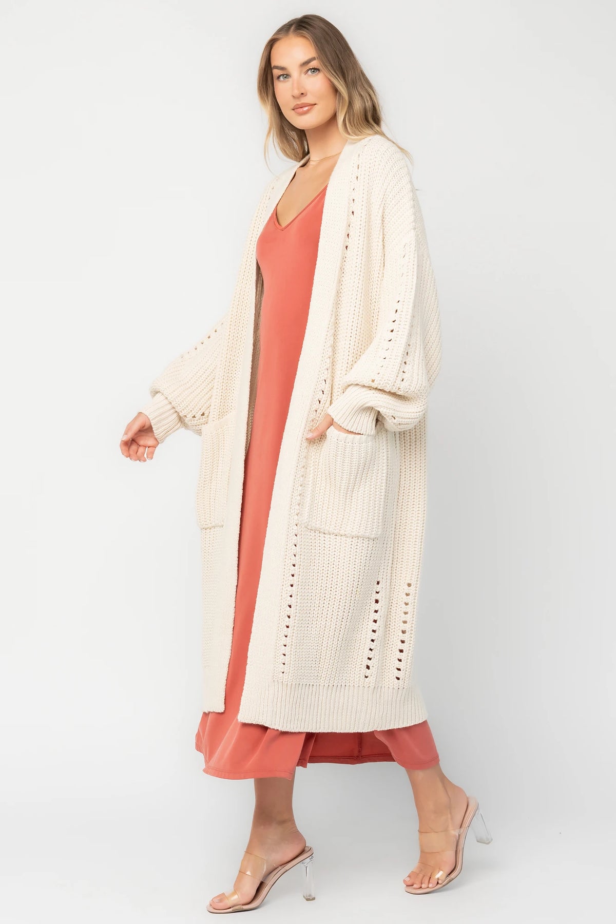 Natural chunky knit longline cardigan with an open front, pointelle detailing, balloon sleeves, ribbed trim, front patch pockets, and an oversized relaxed fit.