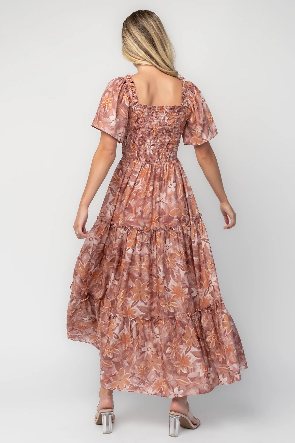 Model wearing the Southampton Smocked Maxi Dress in Dusty Mauve Floral featuring a square neckline, flutter sleeves with ruffle trim, a fully smocked bodice, and a flowing tiered maxi skirt with a dusty mauve floral print.