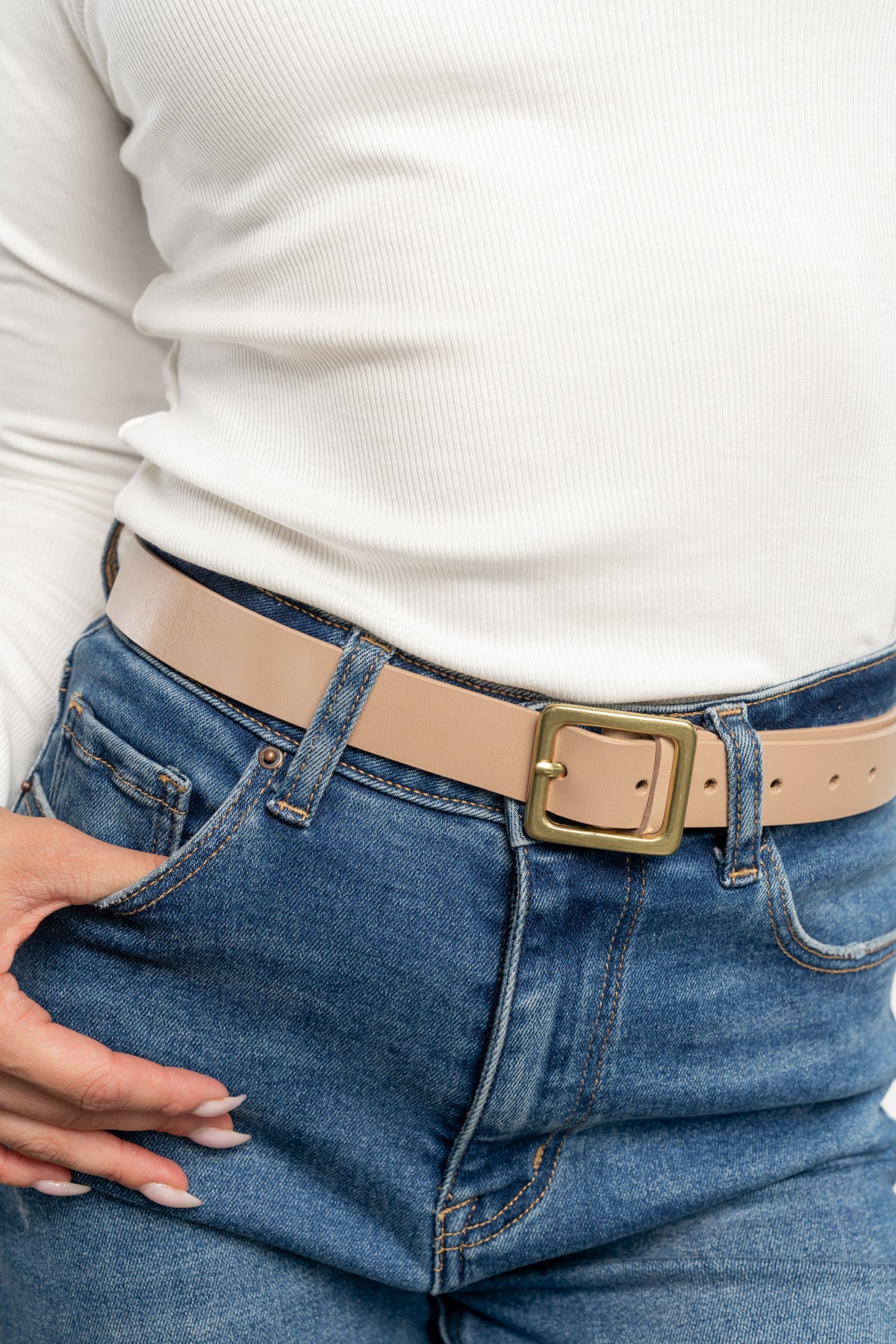 Styled shot of the Deborah Buckle Belt worn with high-rise jeans, showing how the nude beige belt cinches the waist for a polished silhouette.
