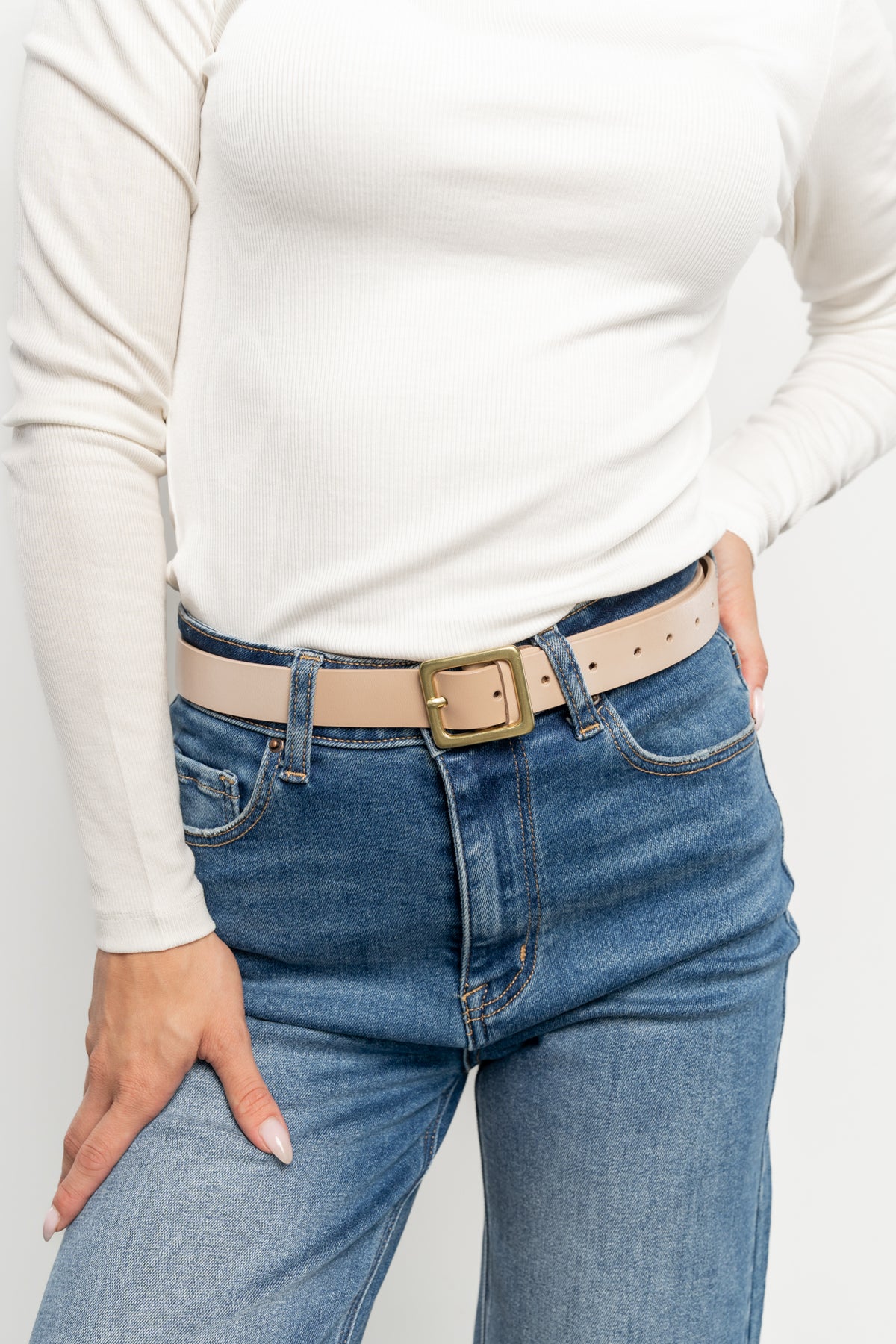 On-model image of the Deborah Buckle Belt paired with a skirt, demonstrating versatile waist and hip styling in a timeless nude beige tone.