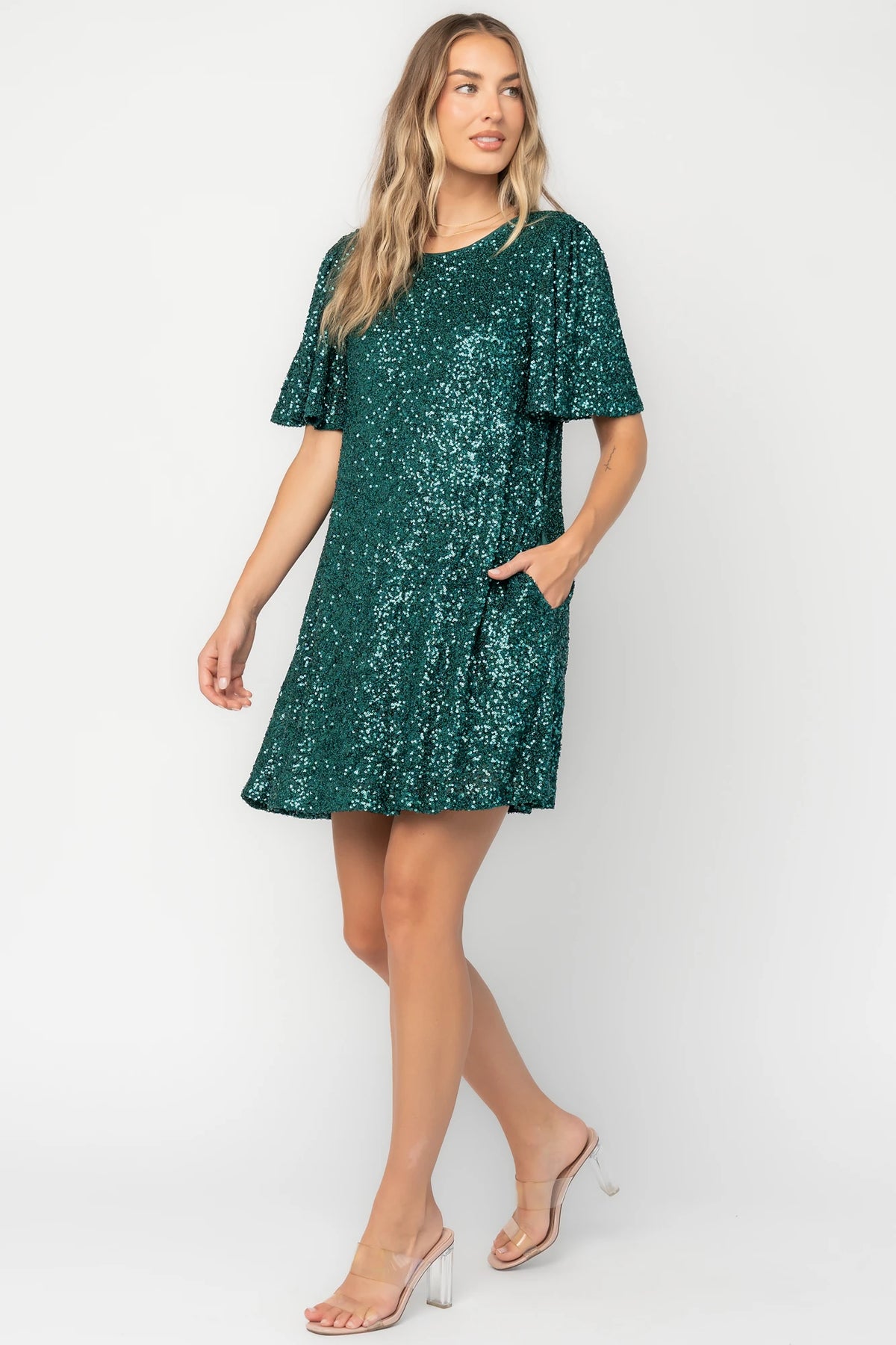 Emerald liquid sequin mini shift dress with a round neckline, short flutter sleeves, and a satin bow back detail.