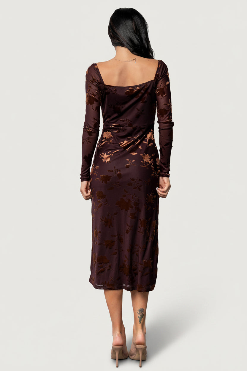 Model seated: Tamara Midi Dress showing square neckline, sheer sleeves with elastic cuff, and skirt drape.