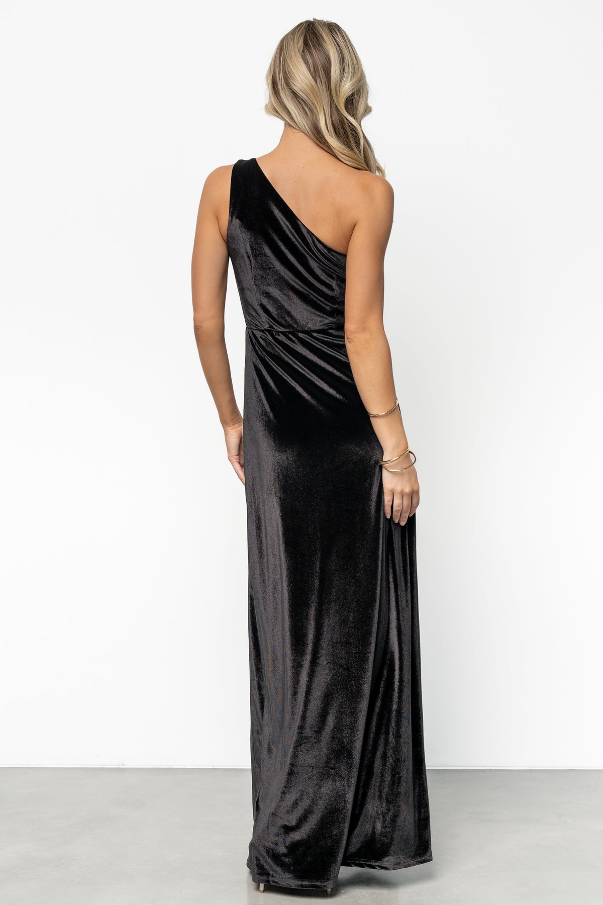 Three-quarter view of the one-shoulder velvet gown in motion, illustrating lining, drape, and flattering silhouette.