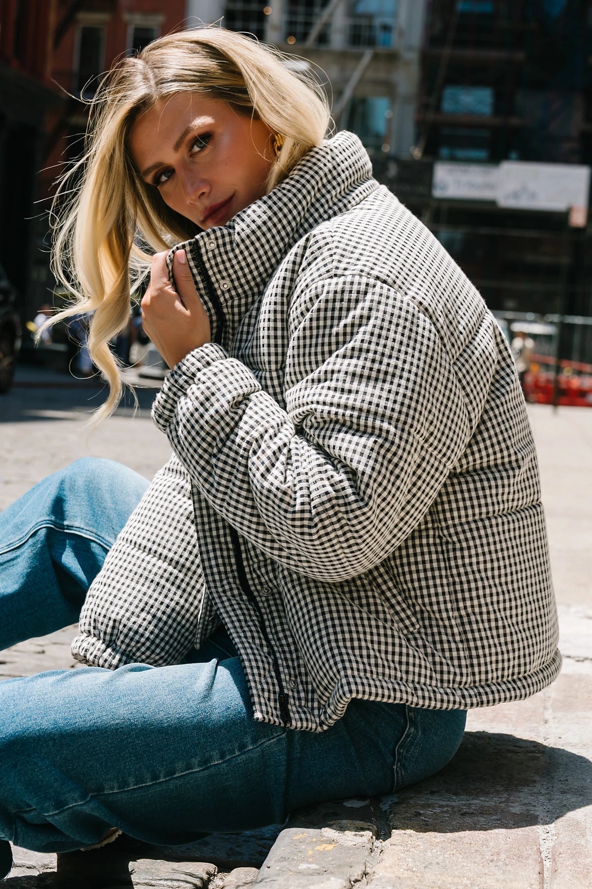 Model wearing the Vivienne Coat featuring a black and white gingham quilted puffer design with a high collar, front zipper and snap-button closure, long sleeves, and a relaxed silhouette.