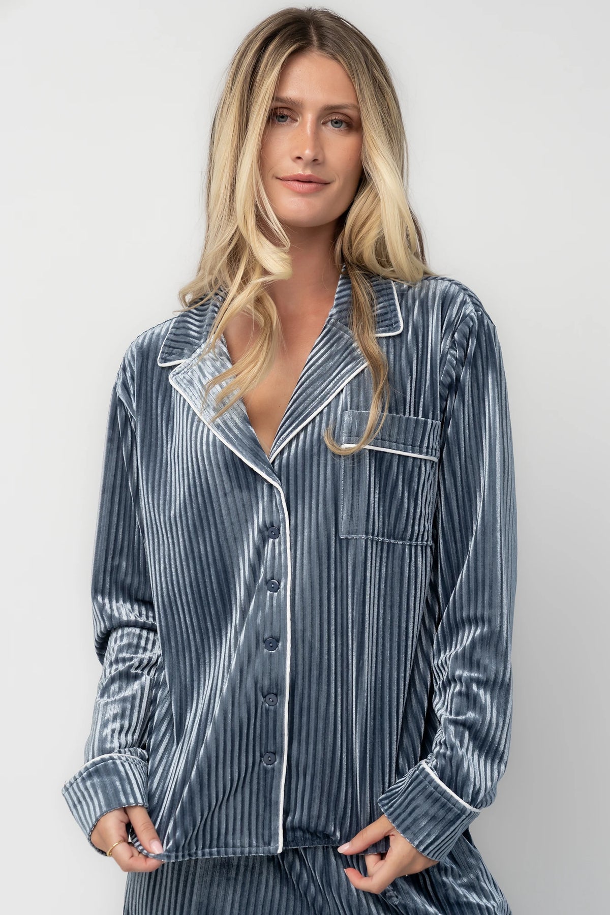 Dusty blue ribbed velvet pajama set with a collared button-front top, chest pocket, long sleeves, and wide-leg pants with an elastic drawstring waist and side pockets.