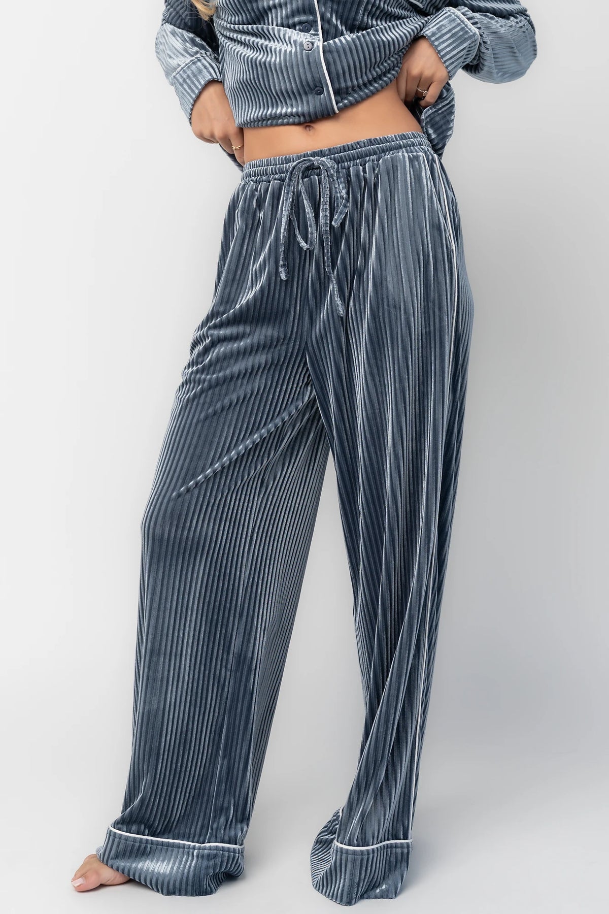 Dusty blue ribbed velvet pajama set with a collared button-front top, chest pocket, long sleeves, and wide-leg pants with an elastic drawstring waist and side pockets.