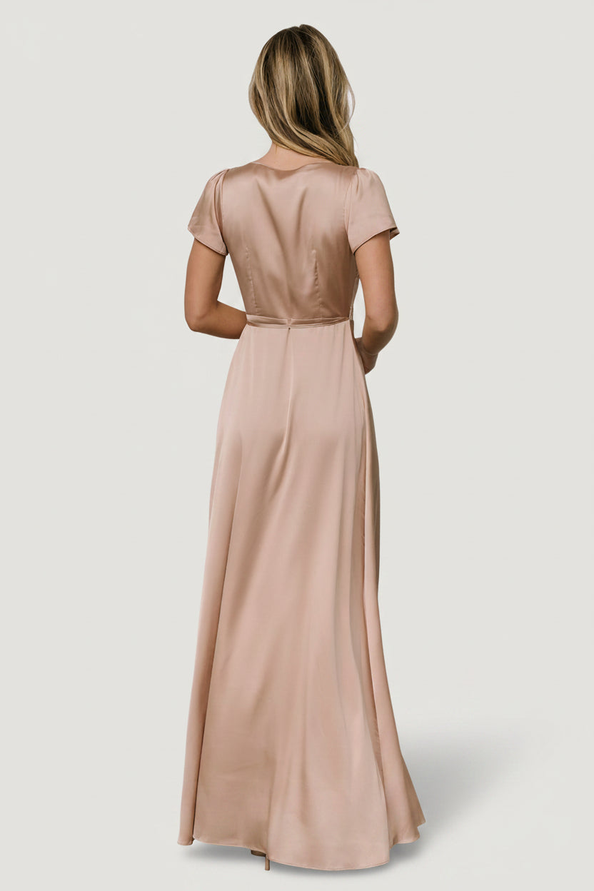 Close-up detail of the Krystal gown's fabric and construction in champagne satin, showing the subtle sheen, stitch lines, and waist tie detail.