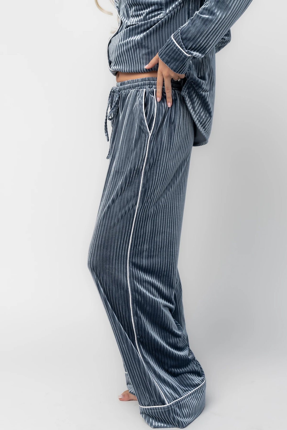 Dusty blue ribbed velvet pajama set with a collared button-front top, chest pocket, long sleeves, and wide-leg pants with an elastic drawstring waist and side pockets.