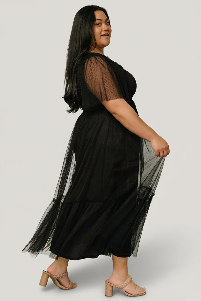 Back and hem detail of the black tulle dress showing layered ruffle, gathered smocking and smooth polyester lining beneath the sheer overlay.