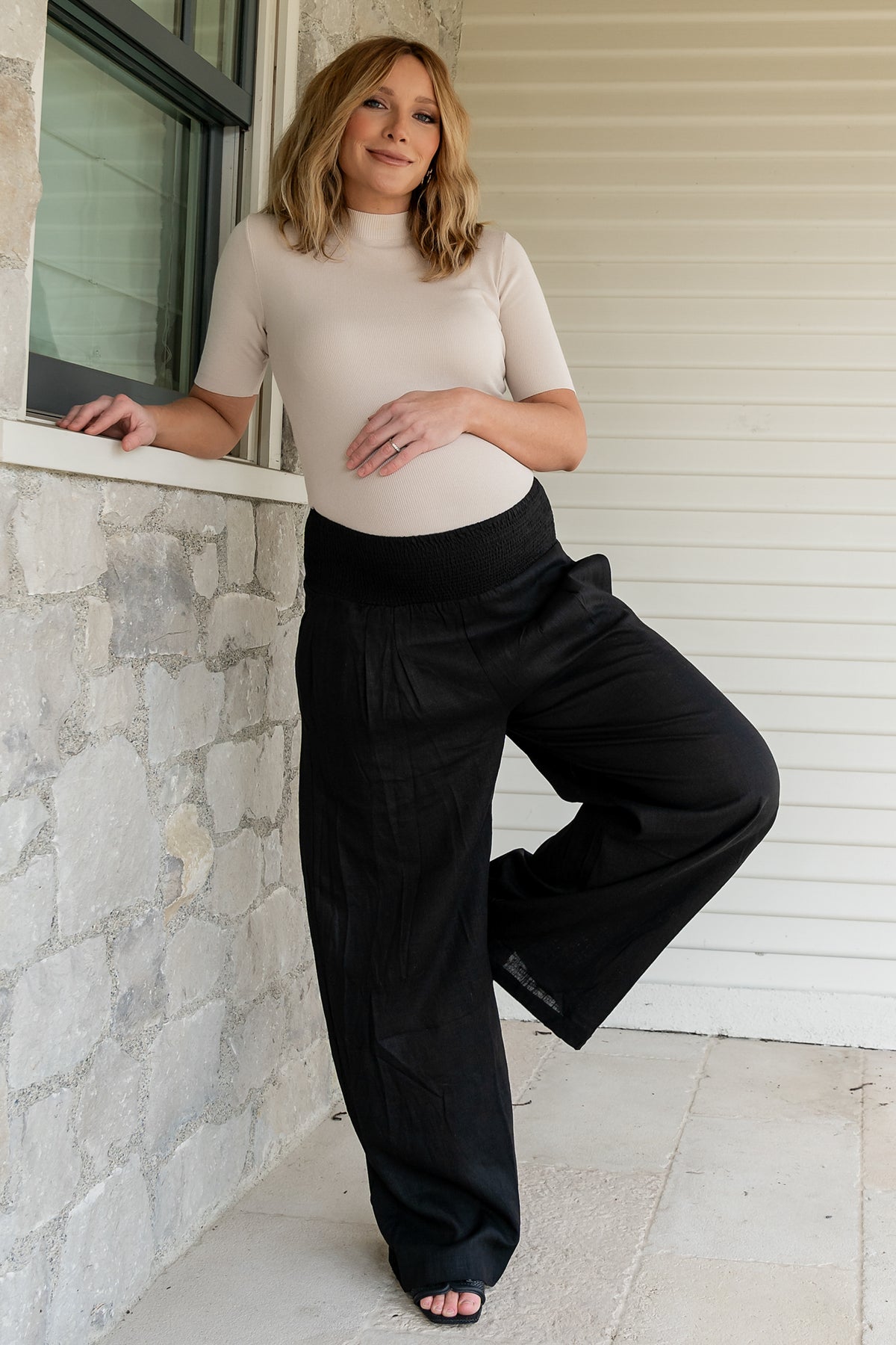 Back and movement shot of Parvati smocked waist pants in black, showing drape and unlined construction.