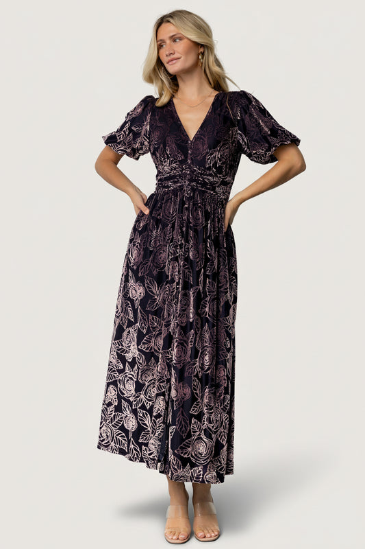 Front view of Dahlia embossed velvet maxi dress in indigo and purple floral, showing V-neck, faux-button placket, short puff sleeves, and pockets.
