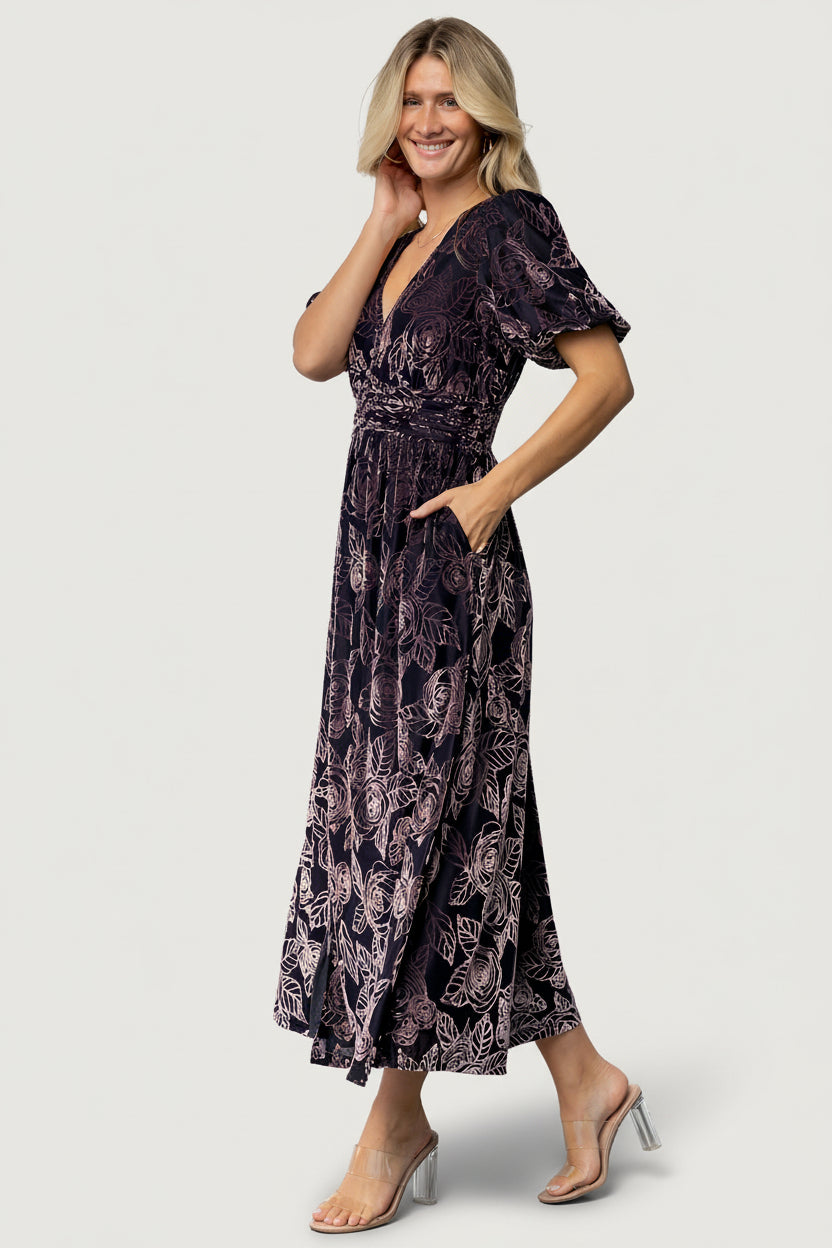Side view of Dahlia maxi dress in indigo and purple floral, showing silhouette, short puff sleeve, and side pocket detail.