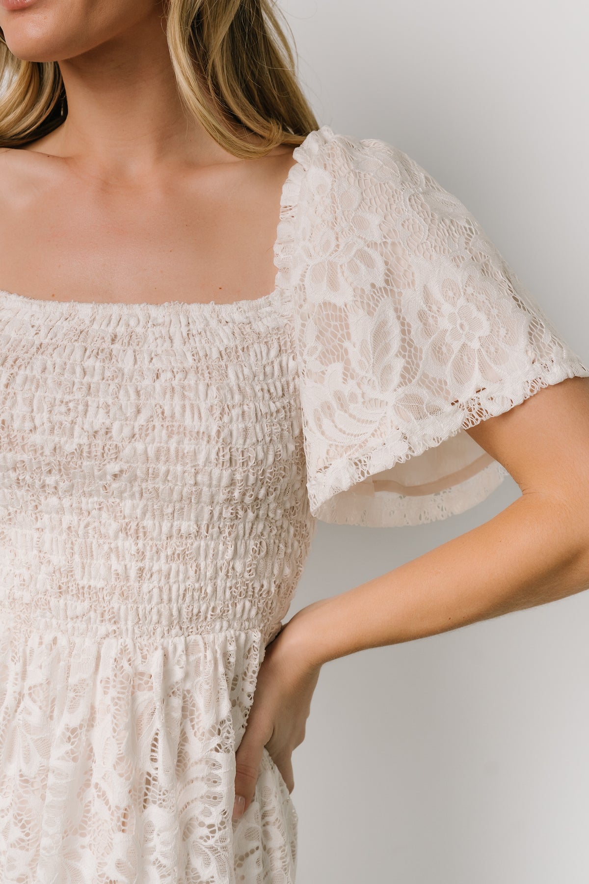 Side view of off-white smocked lace maxi dress that emphasizes the flowing tiers, gentle A-line shape, and lightweight fabric.