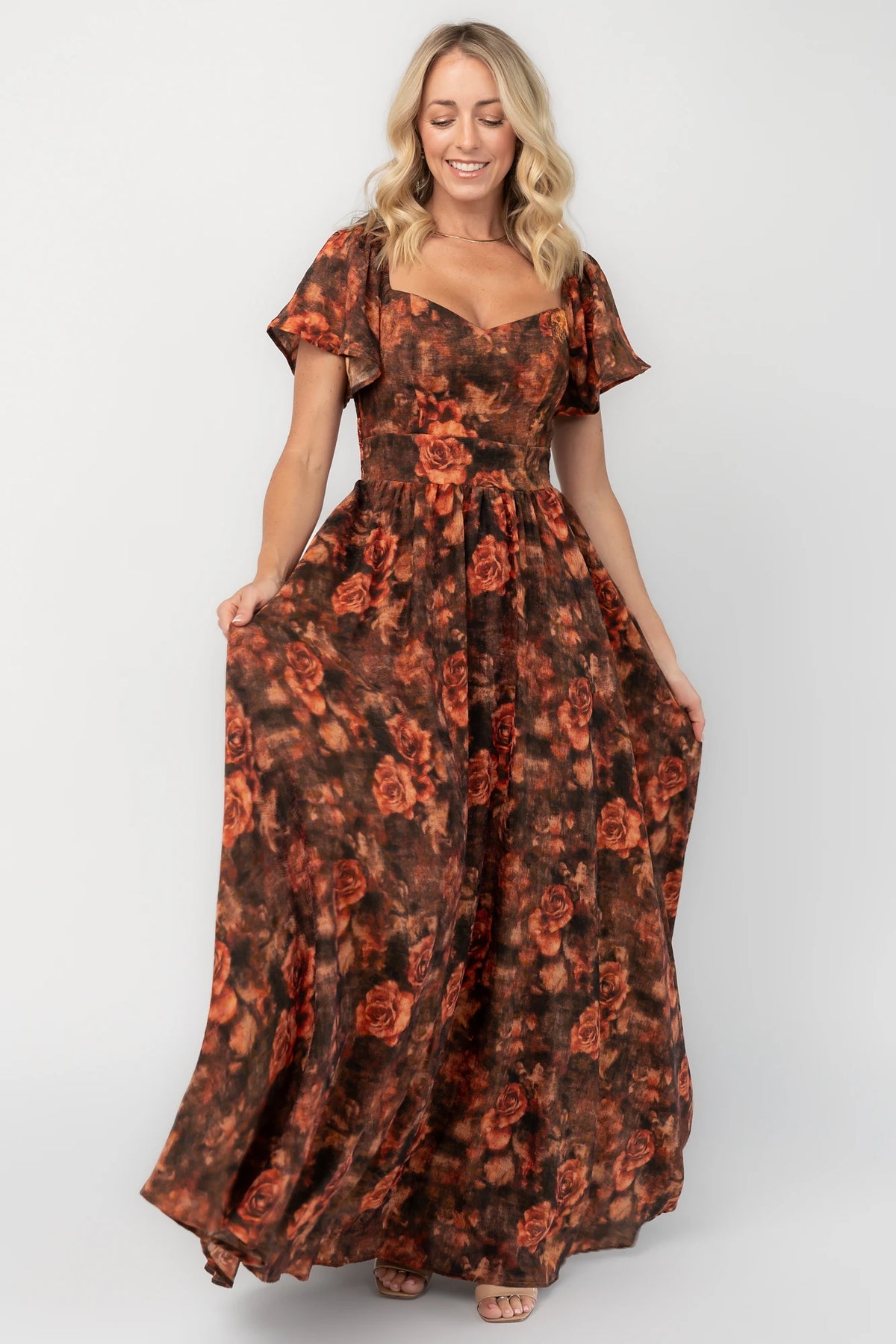 Dark rust floral shimmer maxi dress with a sweetheart neckline, flutter sleeves, empire waist, smocked back, and flowing full-length skirt.