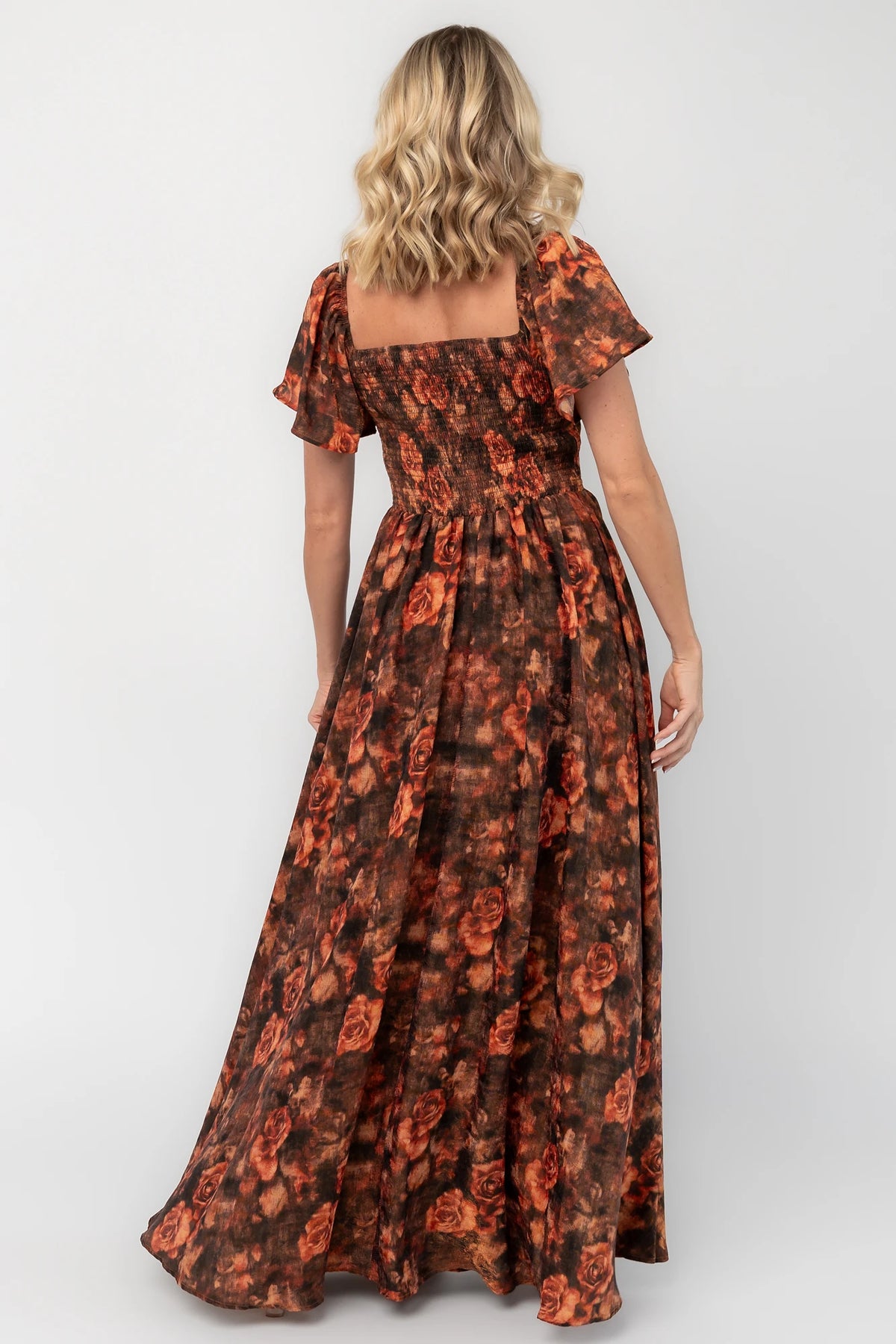 Dark rust floral shimmer maxi dress with a sweetheart neckline, flutter sleeves, empire waist, smocked back, and flowing full-length skirt.