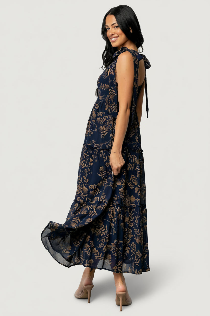Full-length styling image of Anita Maxi Dress in midnight gold floral, paired with gold jewelry to show proportions and wedding-guest ready styling.