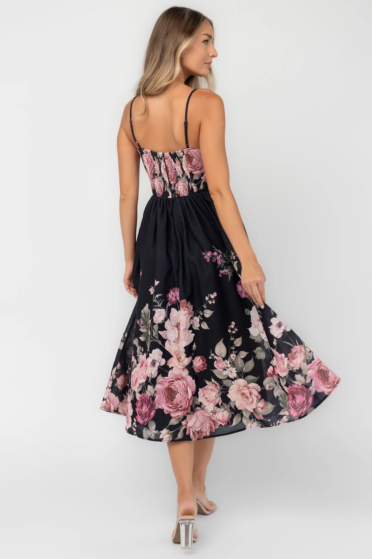 Black floral midi dress with a straight neckline, adjustable spaghetti straps, smocked back, gathered skirt, and side pockets.
