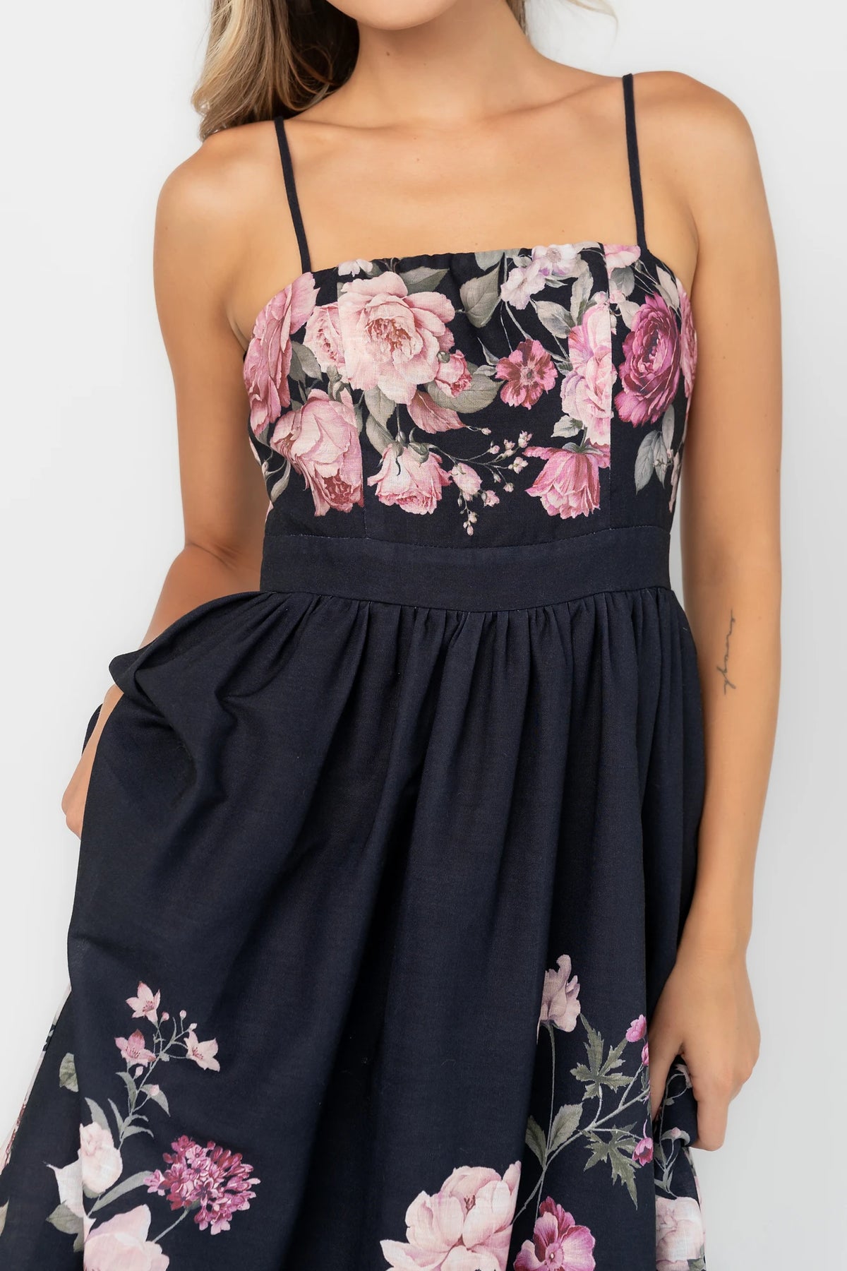 Black floral midi dress with a straight neckline, adjustable spaghetti straps, smocked back, gathered skirt, and side pockets.