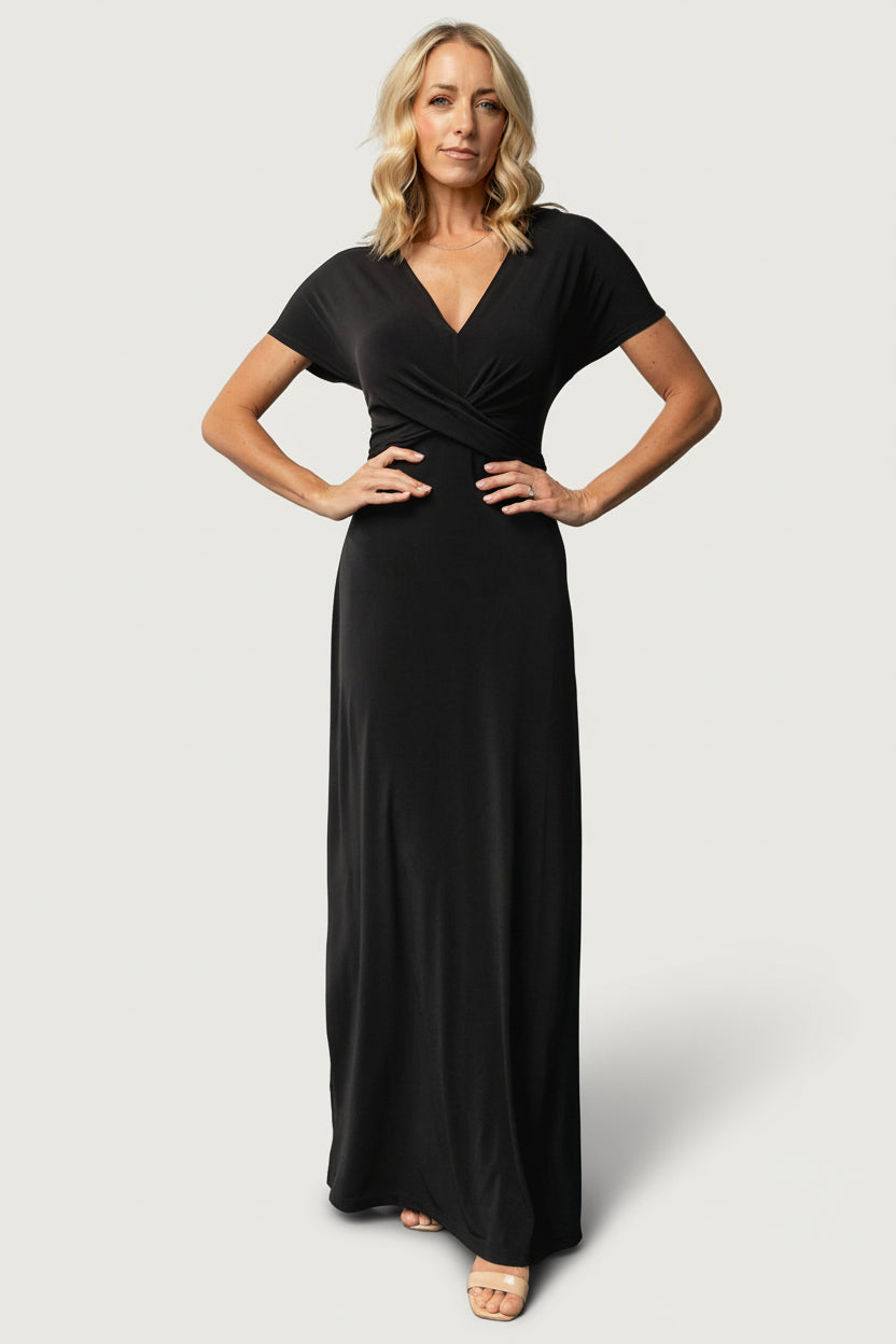 Front view on model wearing the Annaeli black maxi dress showing gathered cross-front, V-neckline, short sleeves, and full-length flowing hem.