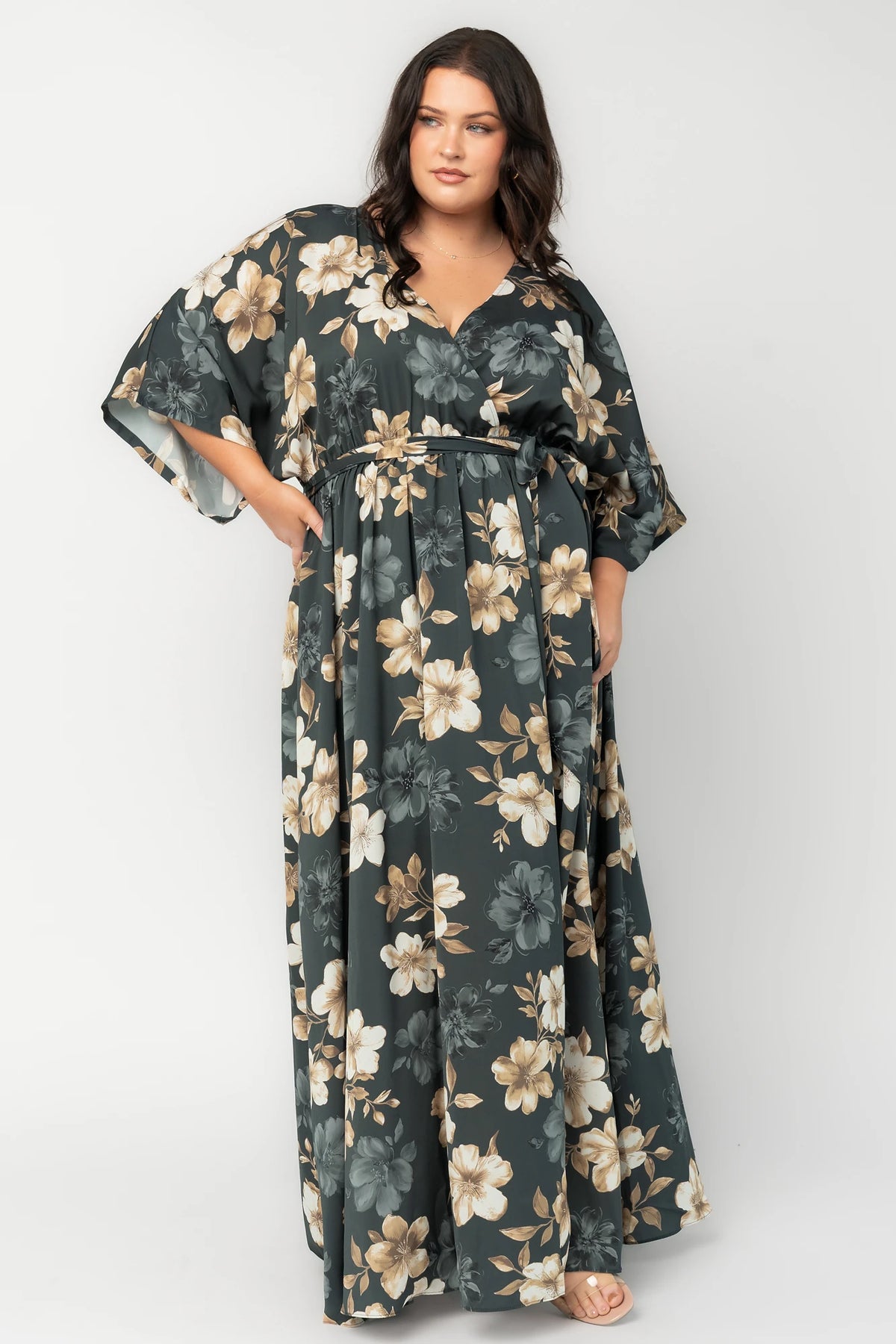 Model wearing a dark jade floral maxi dress with a surplice V-neckline, kimono sleeves, and an elastic waist with a removable sash tie.