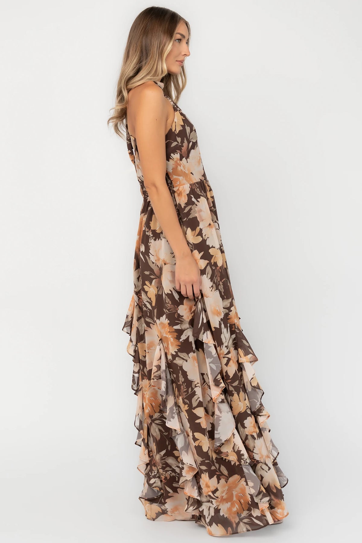 Brown and golden floral chiffon maxi dress with a high halter neckline, cascading ruffle details, smocked back waistband, and a flowing silhouette.