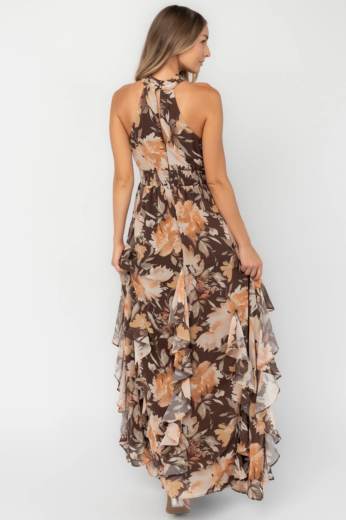 Brown and golden floral chiffon maxi dress with a high halter neckline, cascading ruffle details, smocked back waistband, and a flowing silhouette.