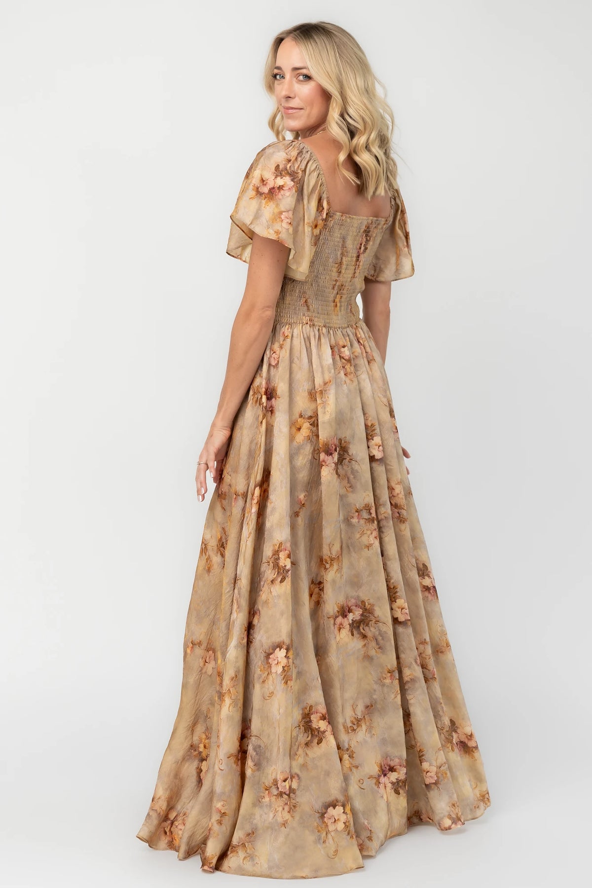 Golden floral maxi dress with a sweetheart neckline, flutter sleeves, smocked back bodice, empire waist, and flowing skirt.