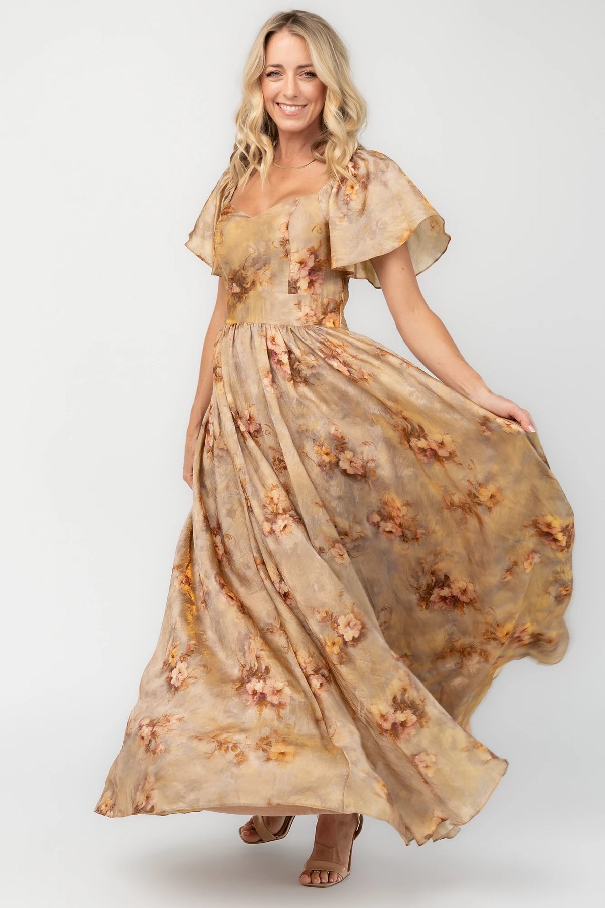 Golden floral maxi dress with a sweetheart neckline, flutter sleeves, smocked back bodice, empire waist, and flowing skirt.