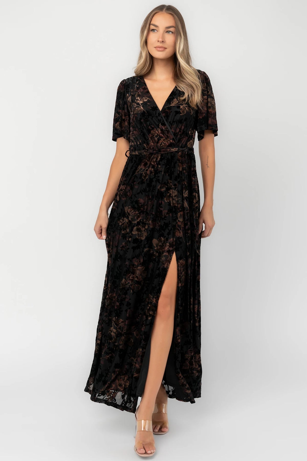 Bronze and black burnout velvet maxi dress with a surplice V-neckline, short flutter sleeves, elastic waist with a removable tie, and a flowing skirt with a side slit.