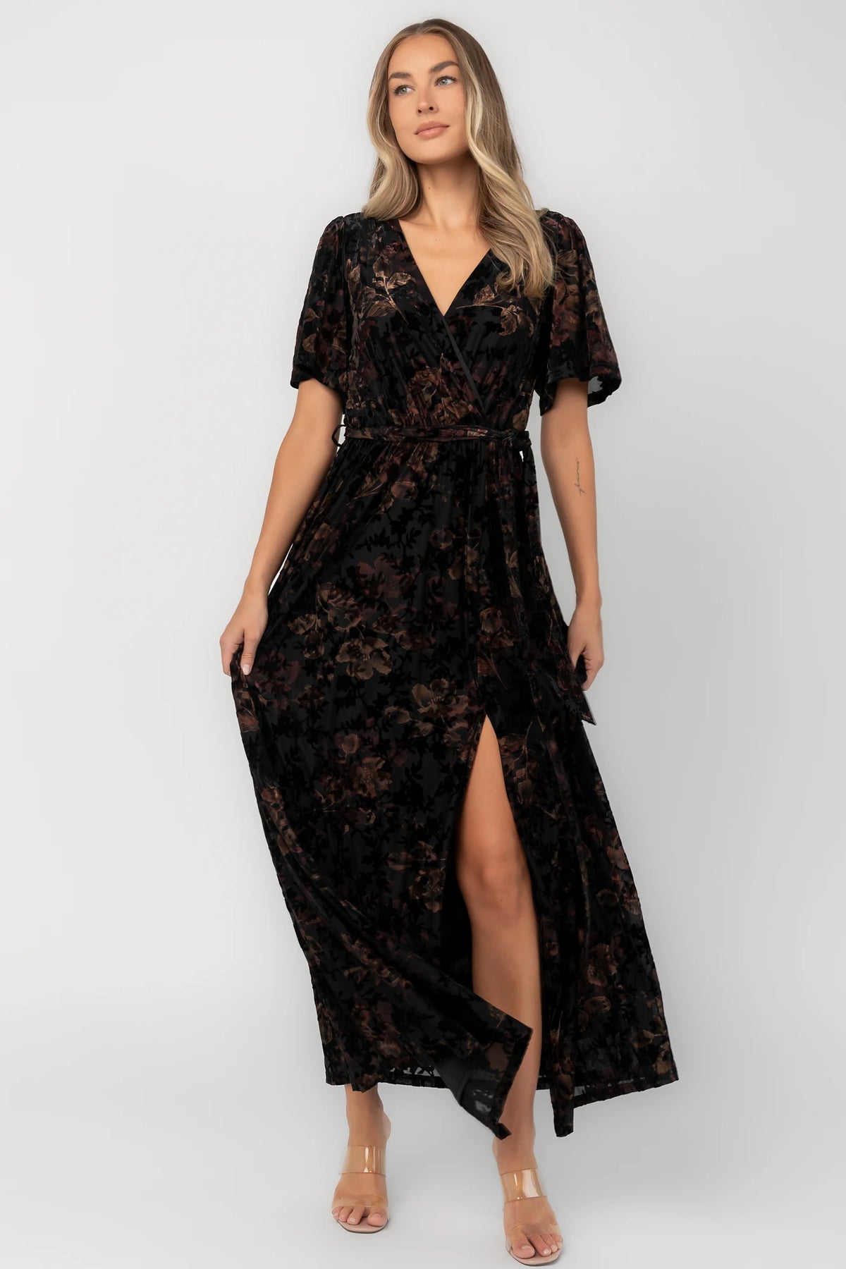 Bronze and black burnout velvet maxi dress with a surplice V-neckline, short flutter sleeves, elastic waist with a removable tie, and a flowing skirt with a side slit.