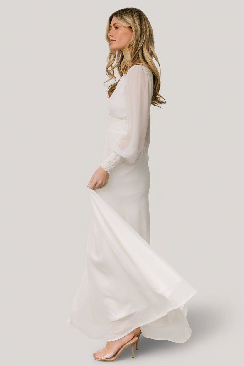 Close-up of the Olivia Maxi Dress white showing deep V-neck detail, smocked waist, and the textured smocked cuffs on the long sleeves.
