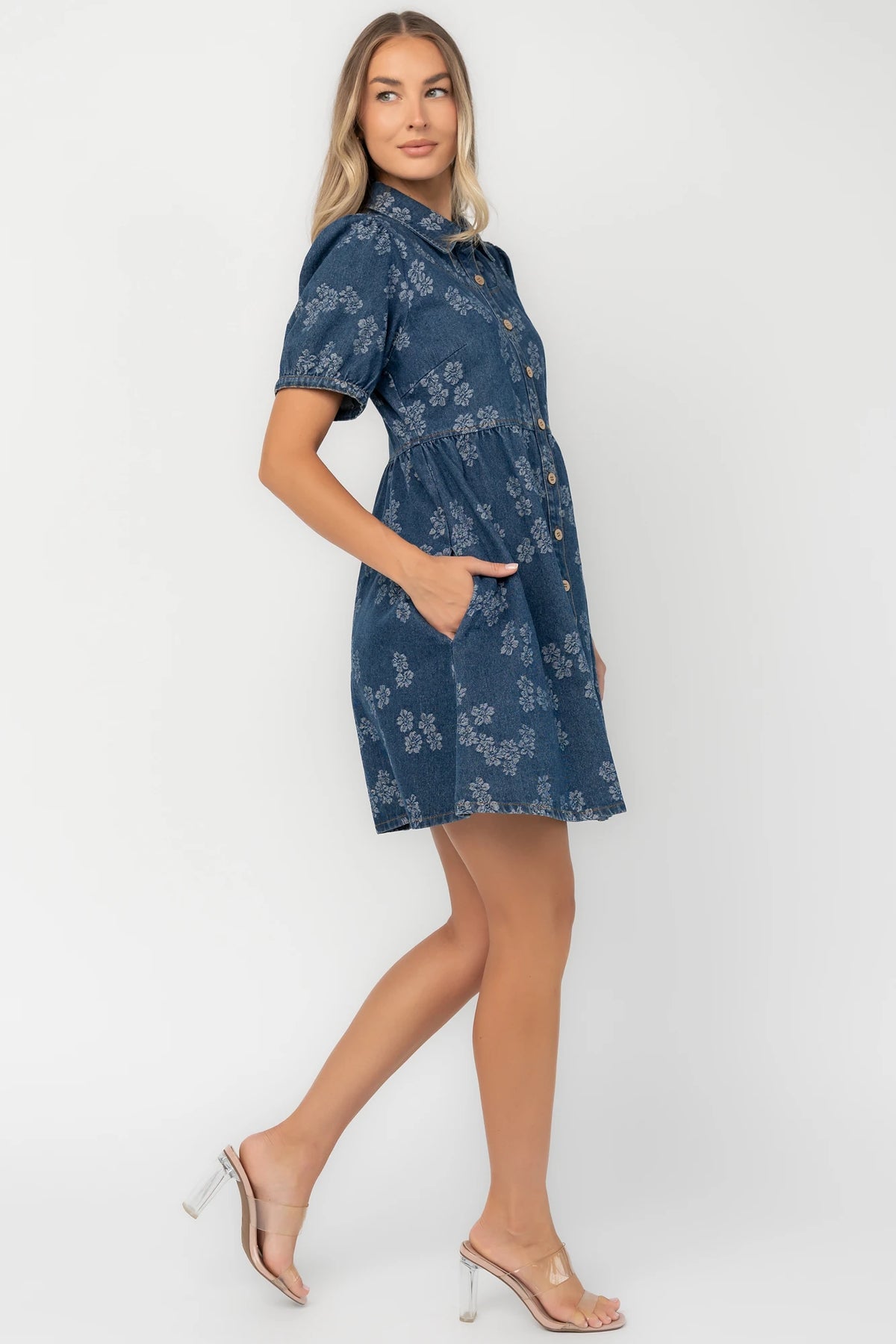 Medium wash floral denim mini dress with a collared neckline, button-front closure, short puff sleeves, empire waist, and side pockets.