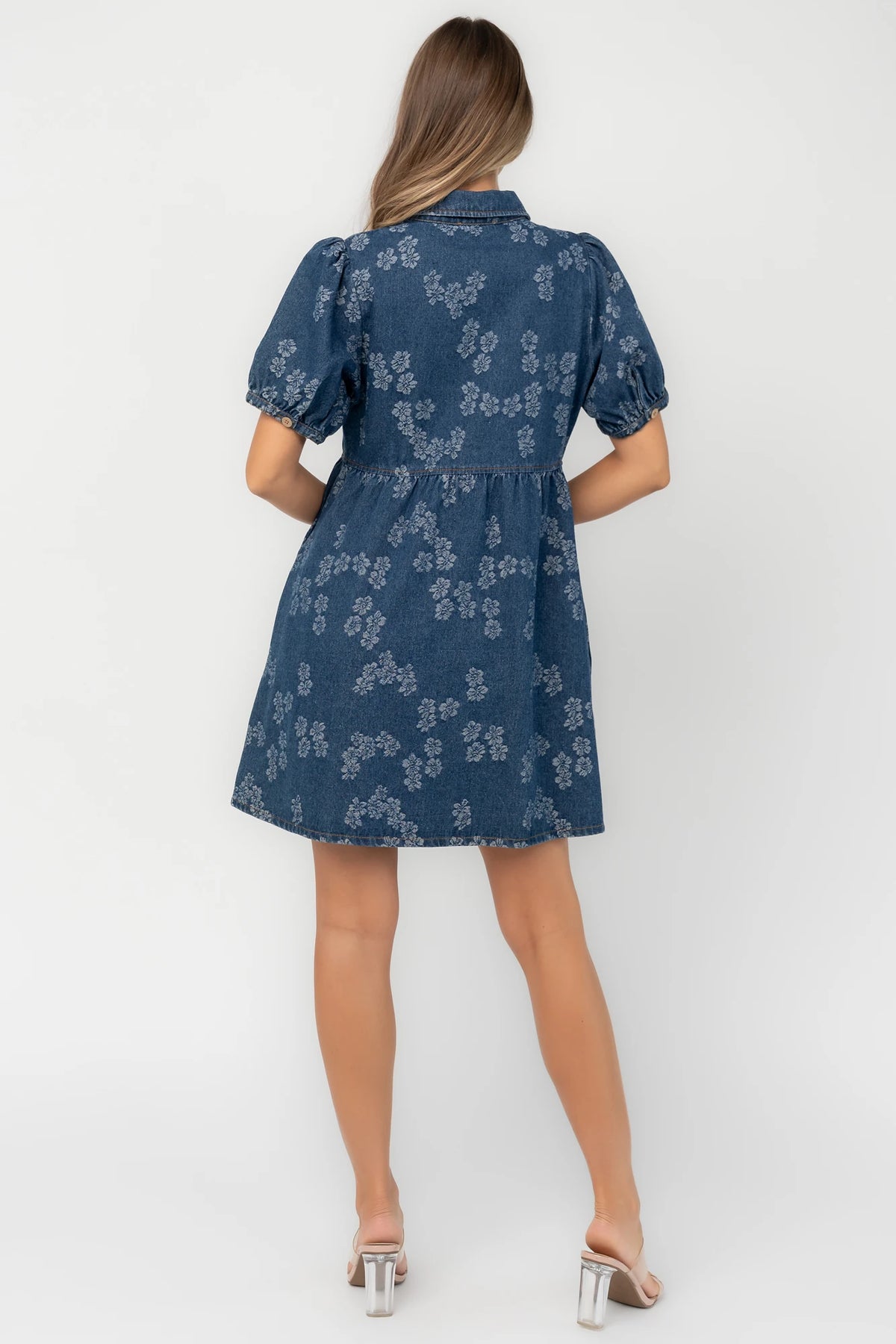 Medium wash floral denim mini dress with a collared neckline, button-front closure, short puff sleeves, empire waist, and side pockets.